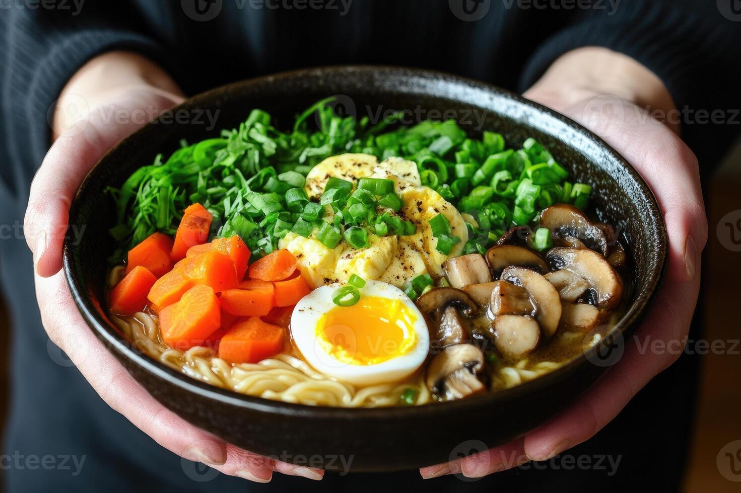 Chef holding bowl of ramen with mushrooms, eggs, carrots, and greens photo