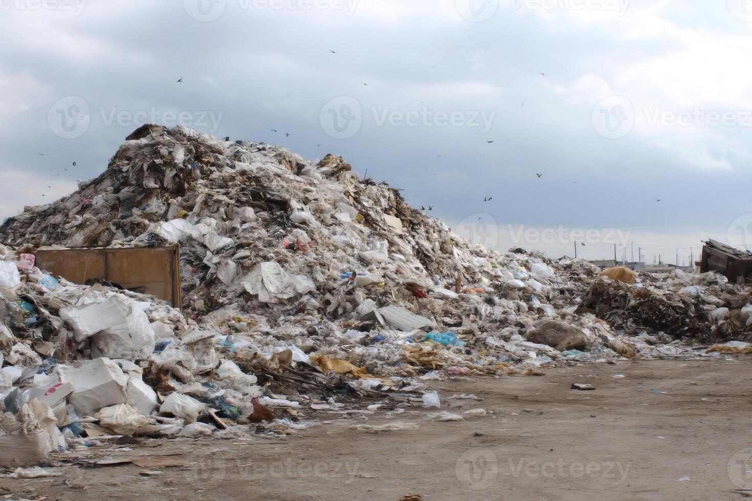 Huge pile of garbage polluting the environment under cloudy sky photo