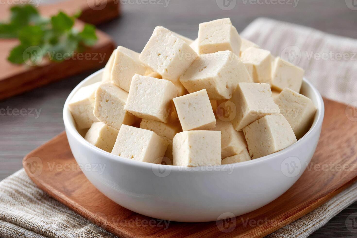 Bowl of diced tofu cubes on wooden board with parsley sprig photo