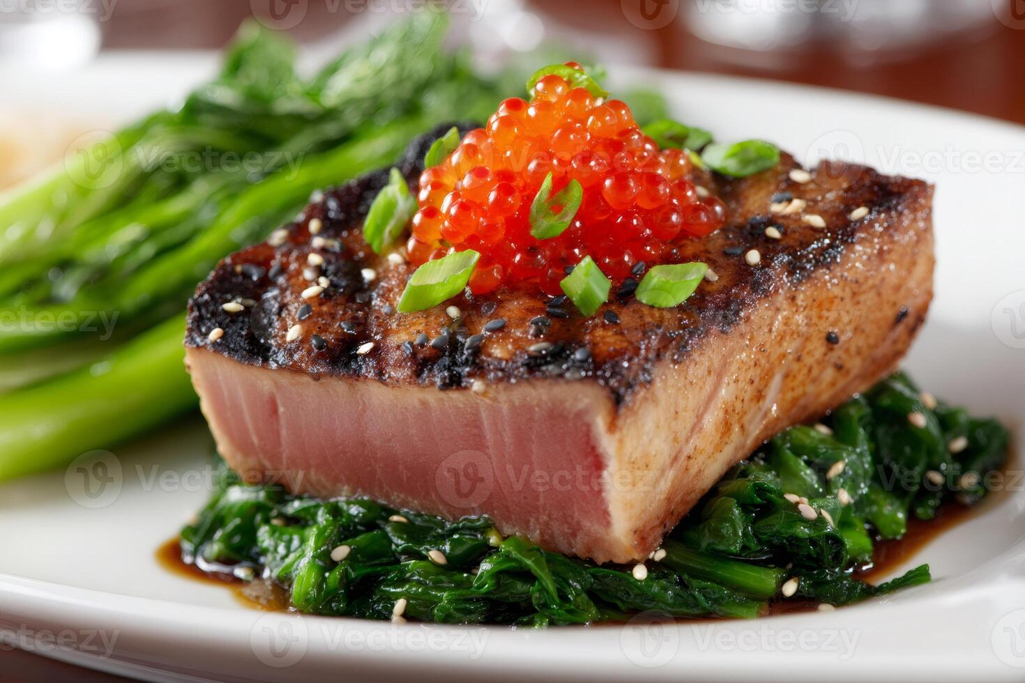 Seared tuna steak with tobiko and sesame seeds on wilted spinach photo