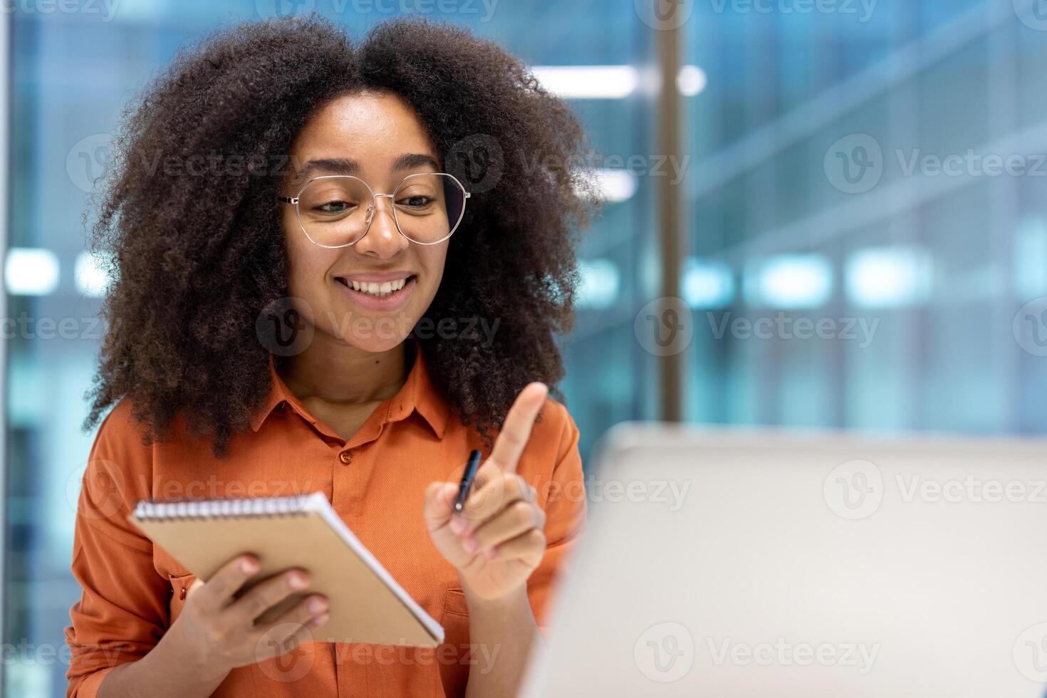 Woman at workplace watching training course webinar, office worker writing training data in notebook, businesswoman smile inside office at workplace. call conference talking photo