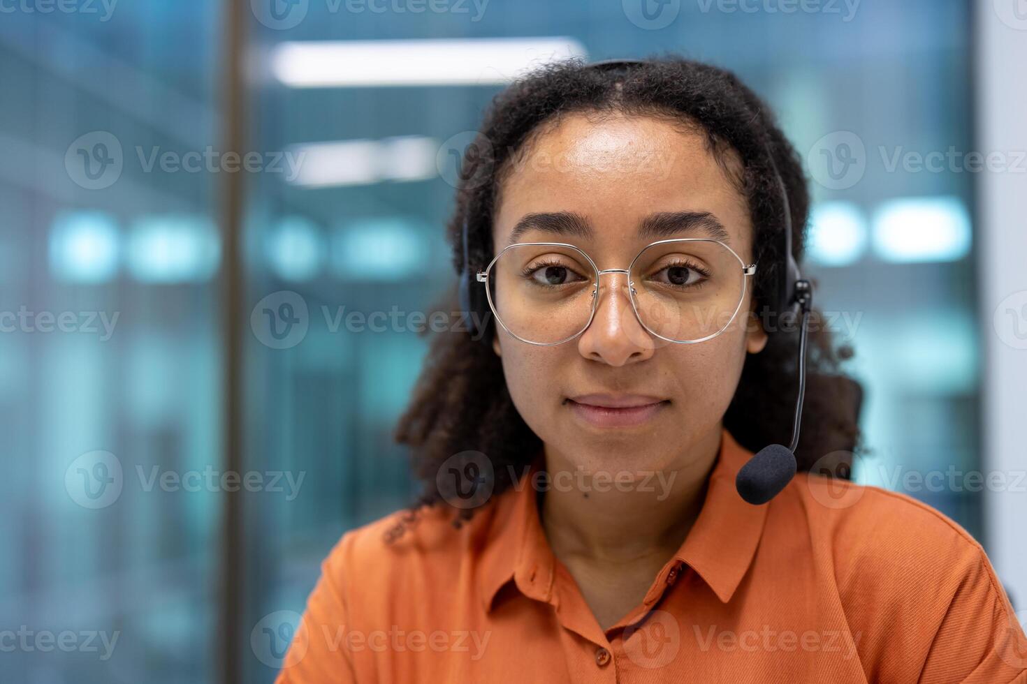Portrait of confident serious woman inside office at workplace. Support worker with headset looking at camera, listening to client interlocutor. photo
