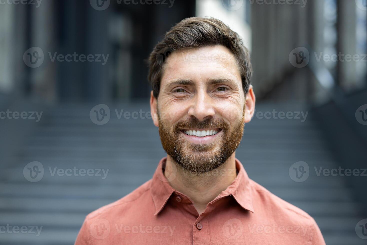 A cheerful man with a warm smile poses in front of a building with a stone staircase, radiating positivity. photo
