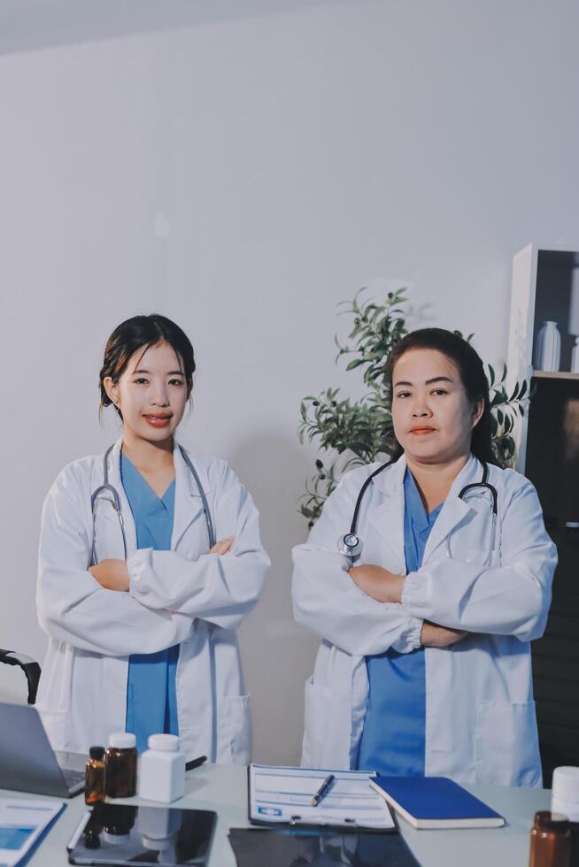Two asian female doctors standing in front of a desk photo