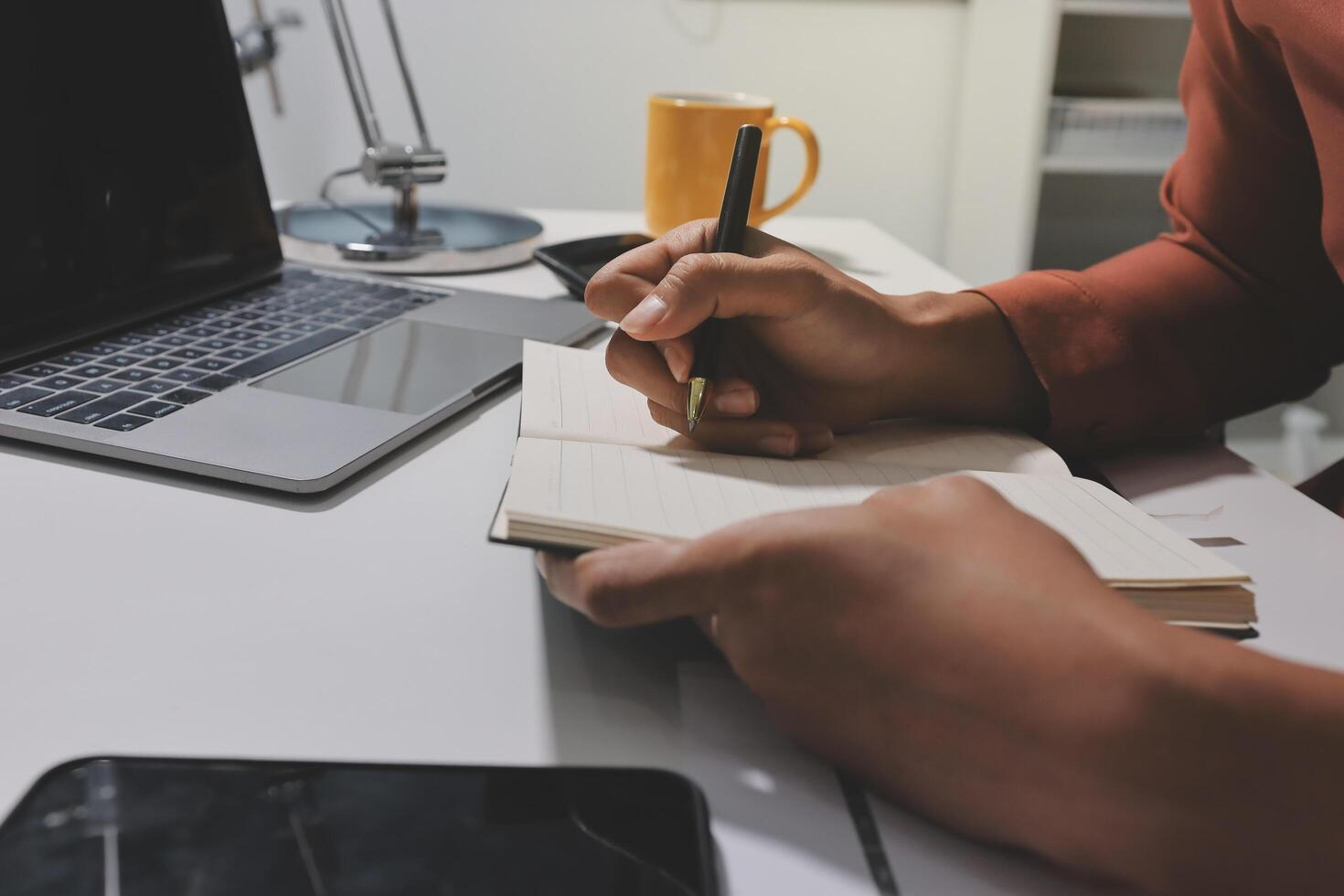 A man writing in a notebook at his desk photo
