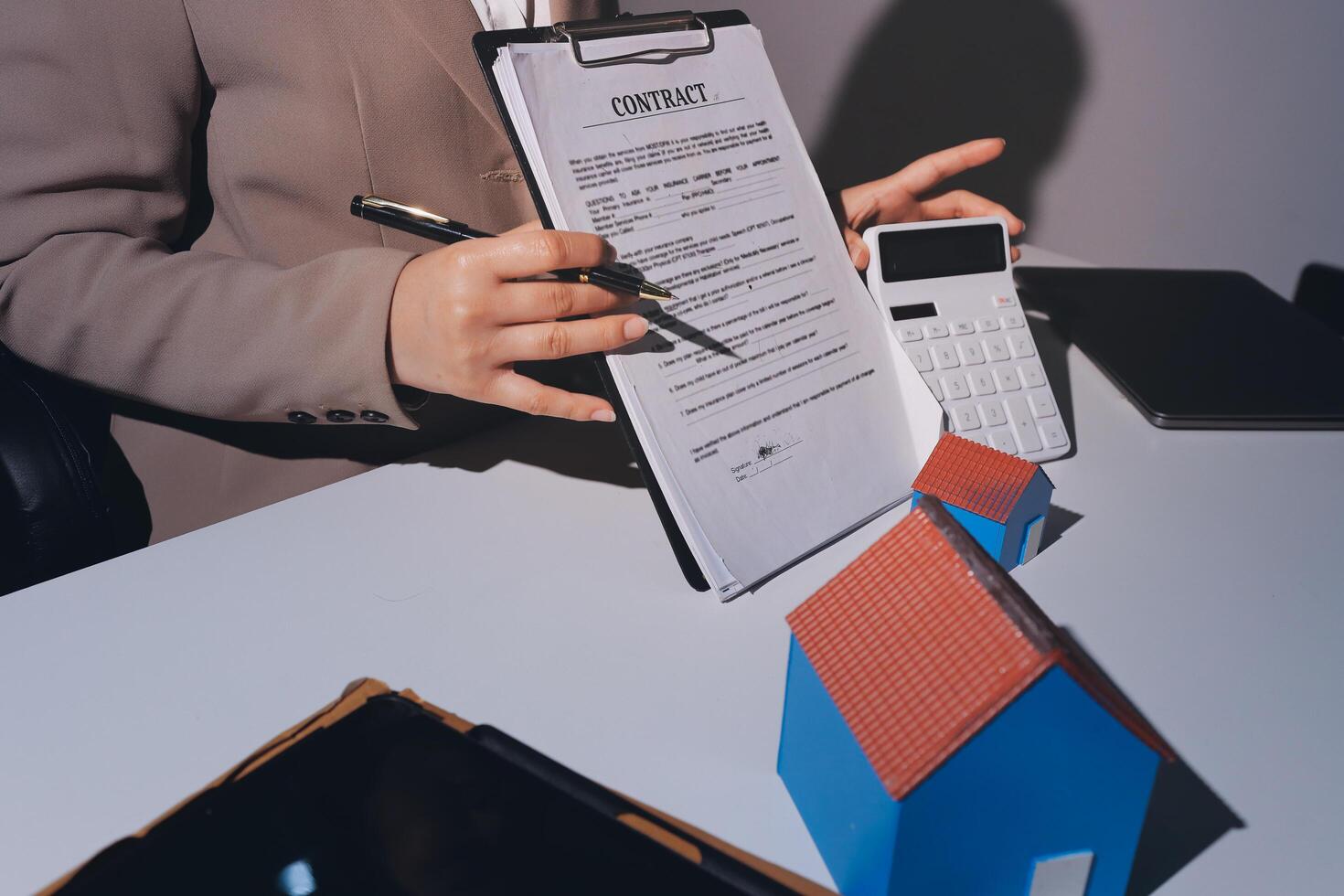 A real estate agent holding a contract and a house model photo