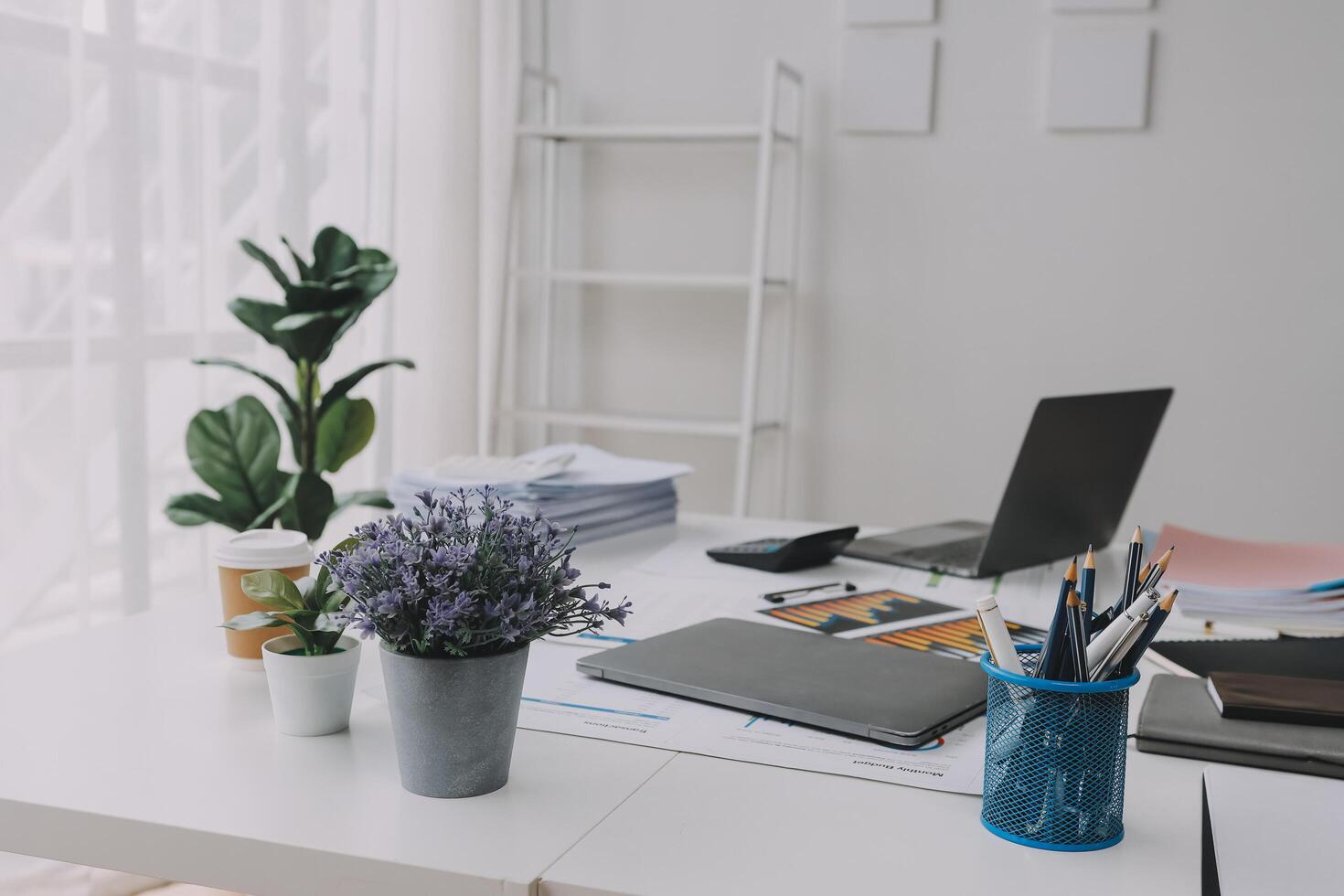 A desk with a laptop, a plant and a vase photo