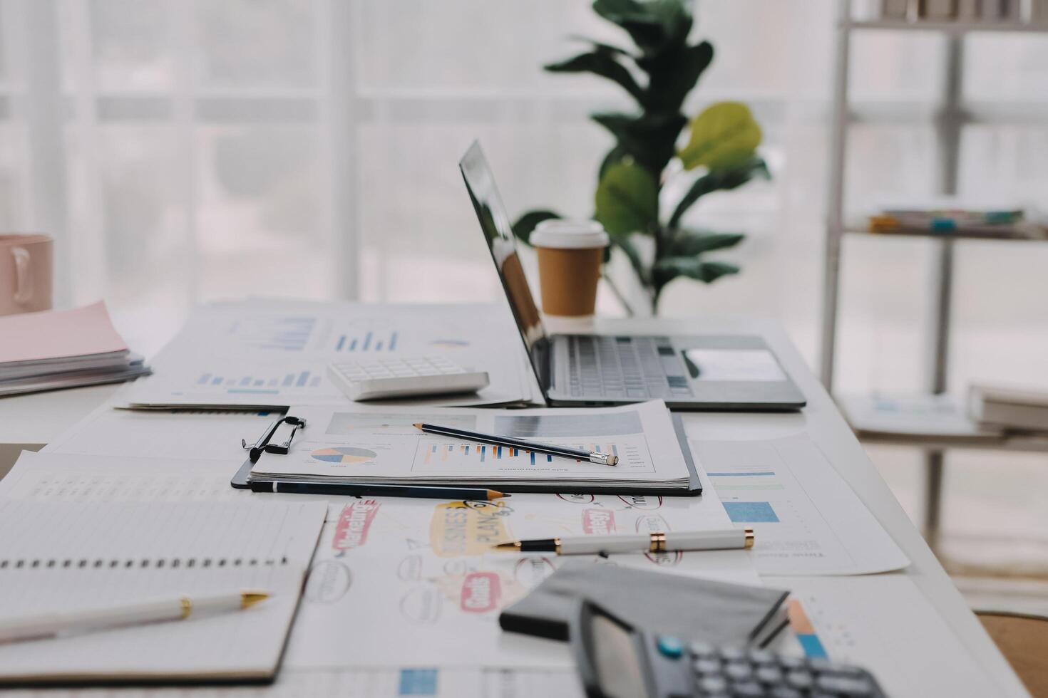 A desk with a laptop, a notebook, and a pen on it photo