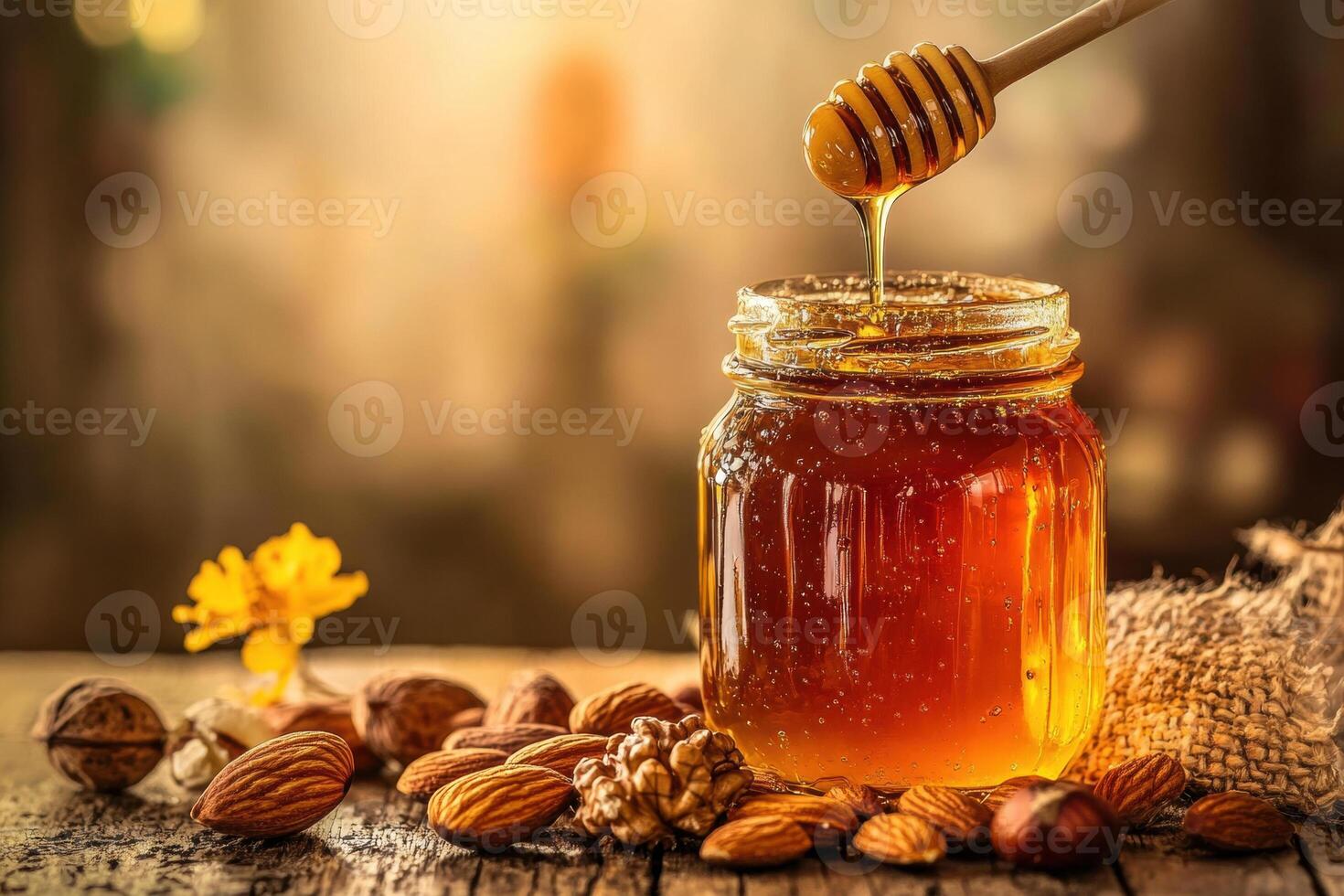 Honey drizzled from a dipper into a jar surrounded by nuts photo