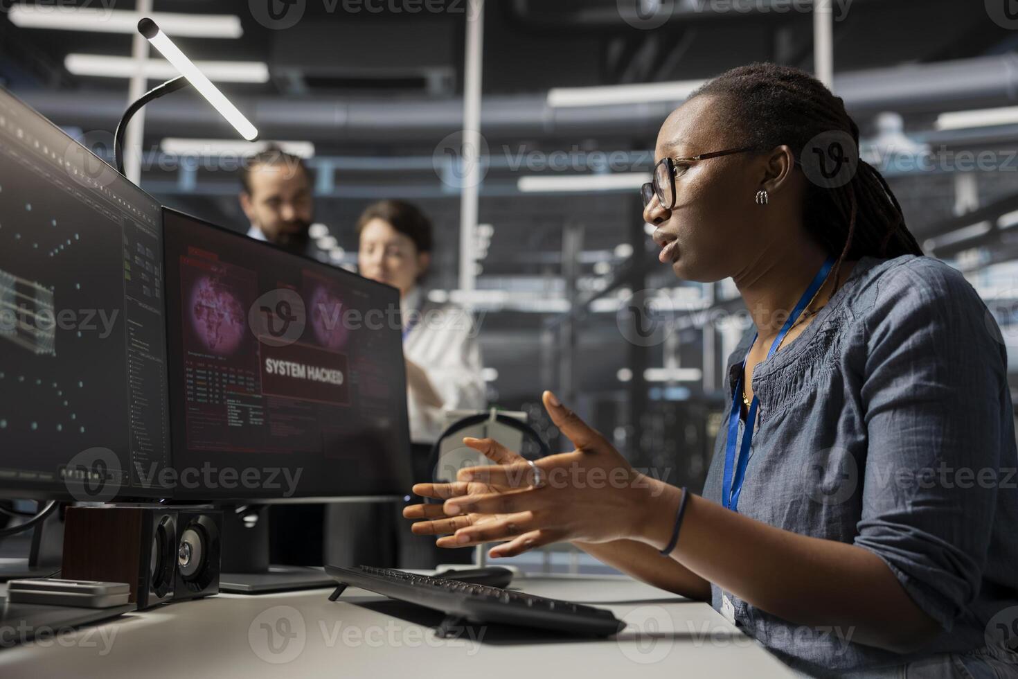 Scared admin in data center panicked by virus alert, initiating protocol to protect critical systems. African American woman in server room assessing compromised gear after hacker attack photo