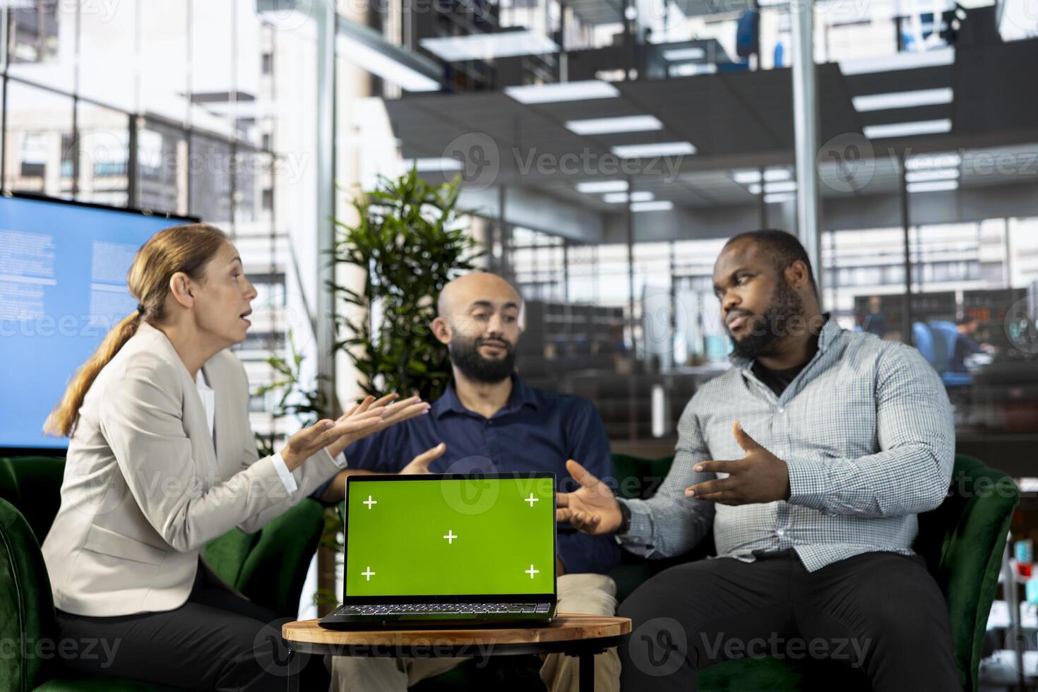 Isolated screen notebook next to multiethnic team working in office, coordinating company administrative operation. Diverse coworkers reviewing business data metrics on chroma key laptop photo