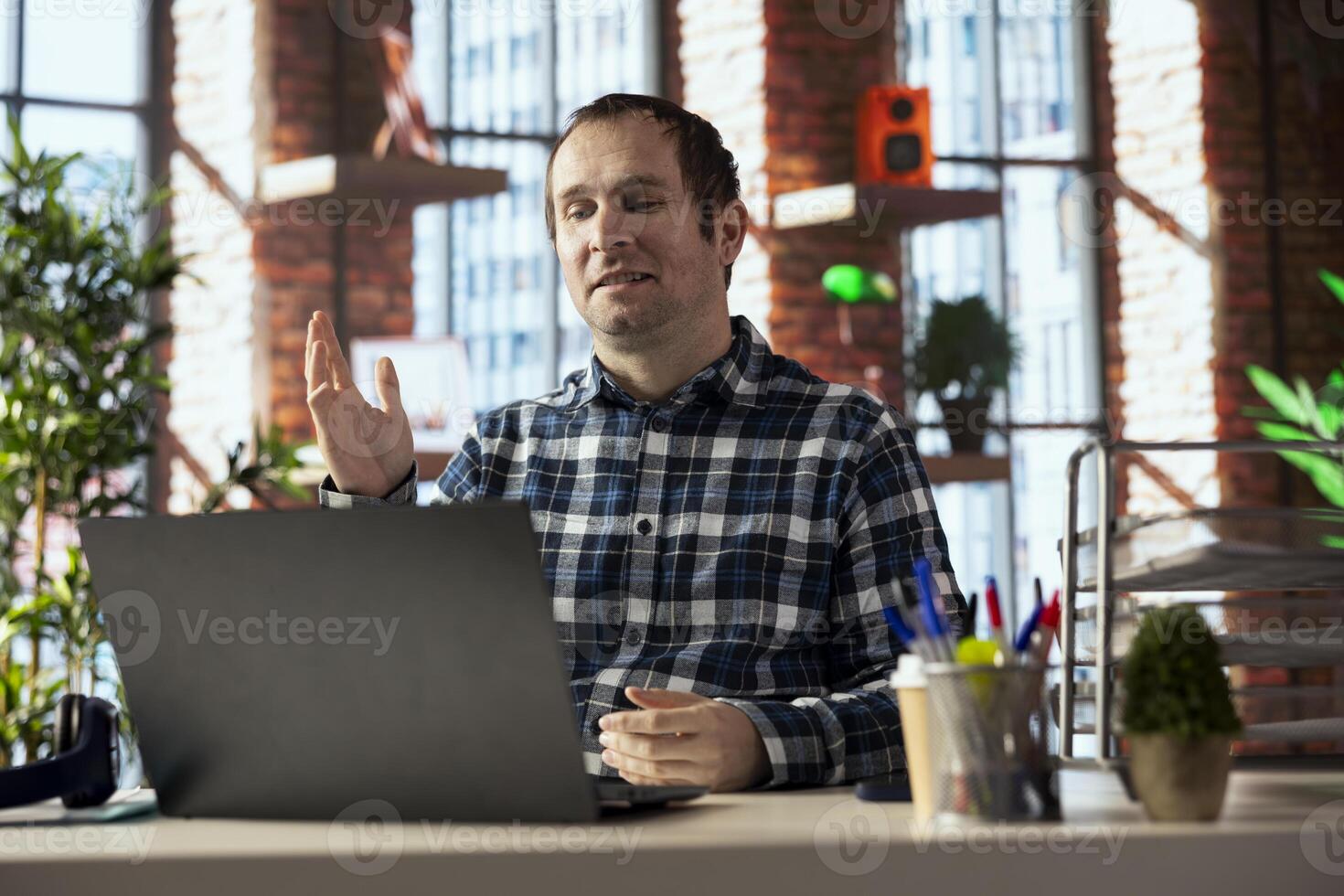 home office employee looking at laptop screen, saluting colleagues during online videocall. Businessperson in home office greeting team members during videoconference meeting on notebook photo