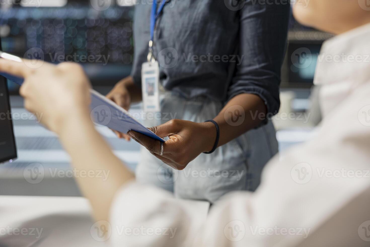 Close up of server room employees reviewing documentation on clipboard ahead of scheduled system audit. Data center coworkers verifying configuration data and compliance standards in office photo