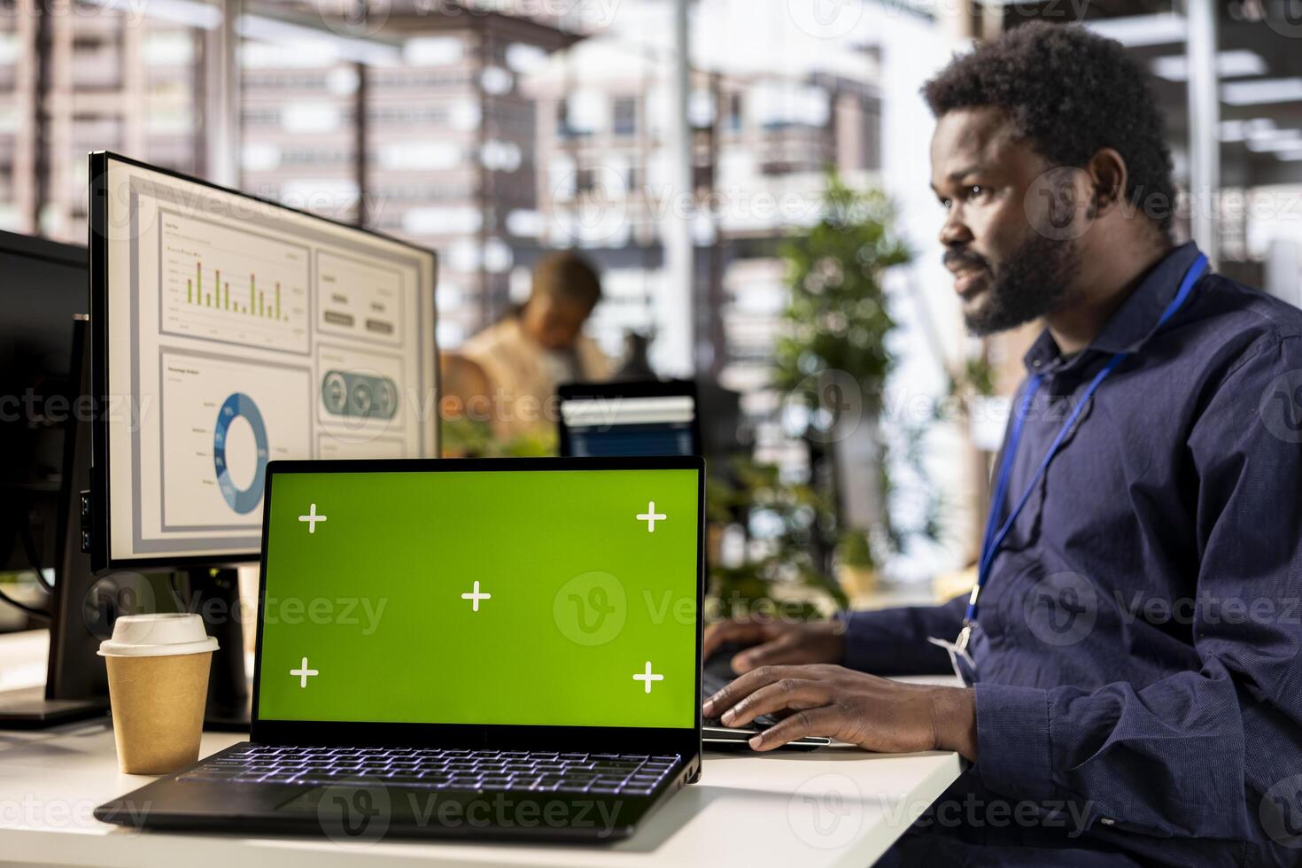 Black general manager studies corporate statistics next to chroma key, working at the office to ensure business success and growth. Male analyst working with numbers, management. photo