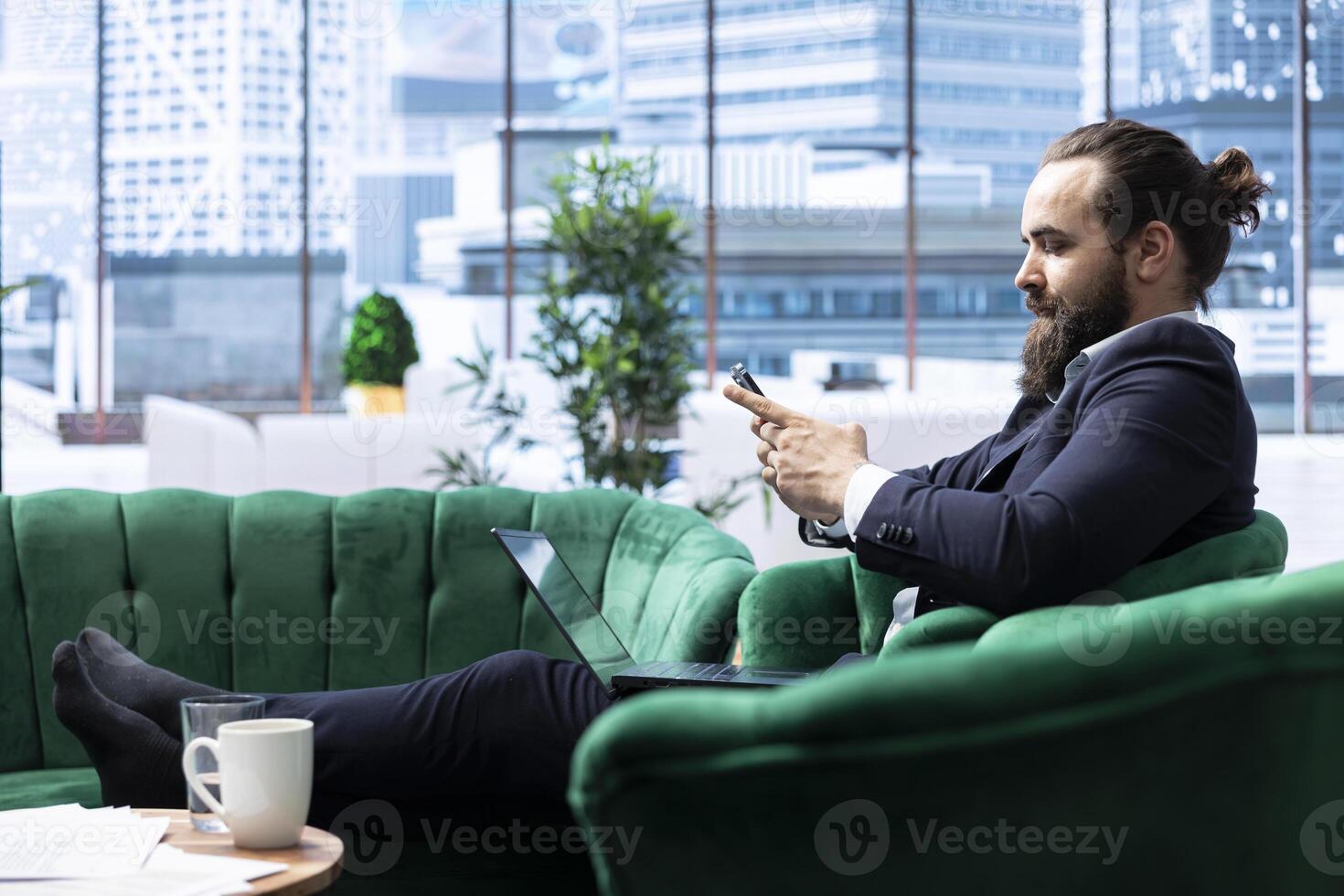 Motivated boss working tirelessly in a high end downtown workspace, reviewing financial forecasts and tracking sales performance. Chief executive officer scrolls smartphone with authority. photo