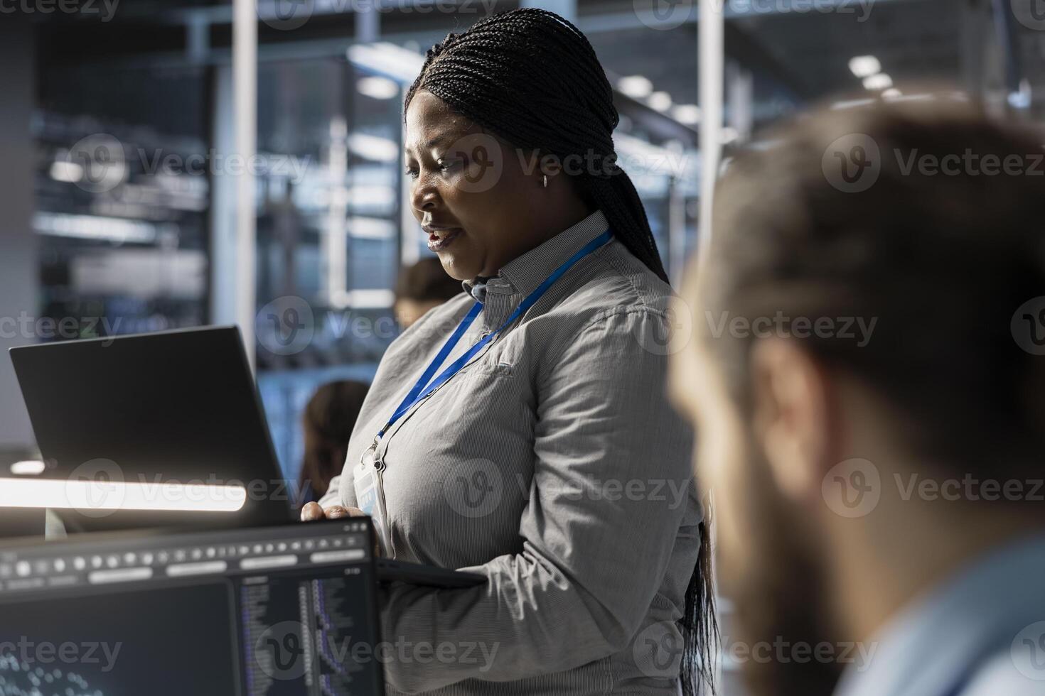 Technician using laptop to oversee server infrastructure powering algorithm training and data inference tasks. Employee using notebook to do maintenance on supercomputers supporting analytics workload photo