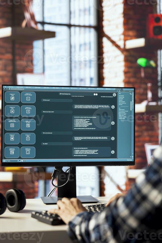 Person seated at desk communicating with AI LLM chatbot software in modern home office. Close up of large language model program interface on computer screen in bright apartment photo