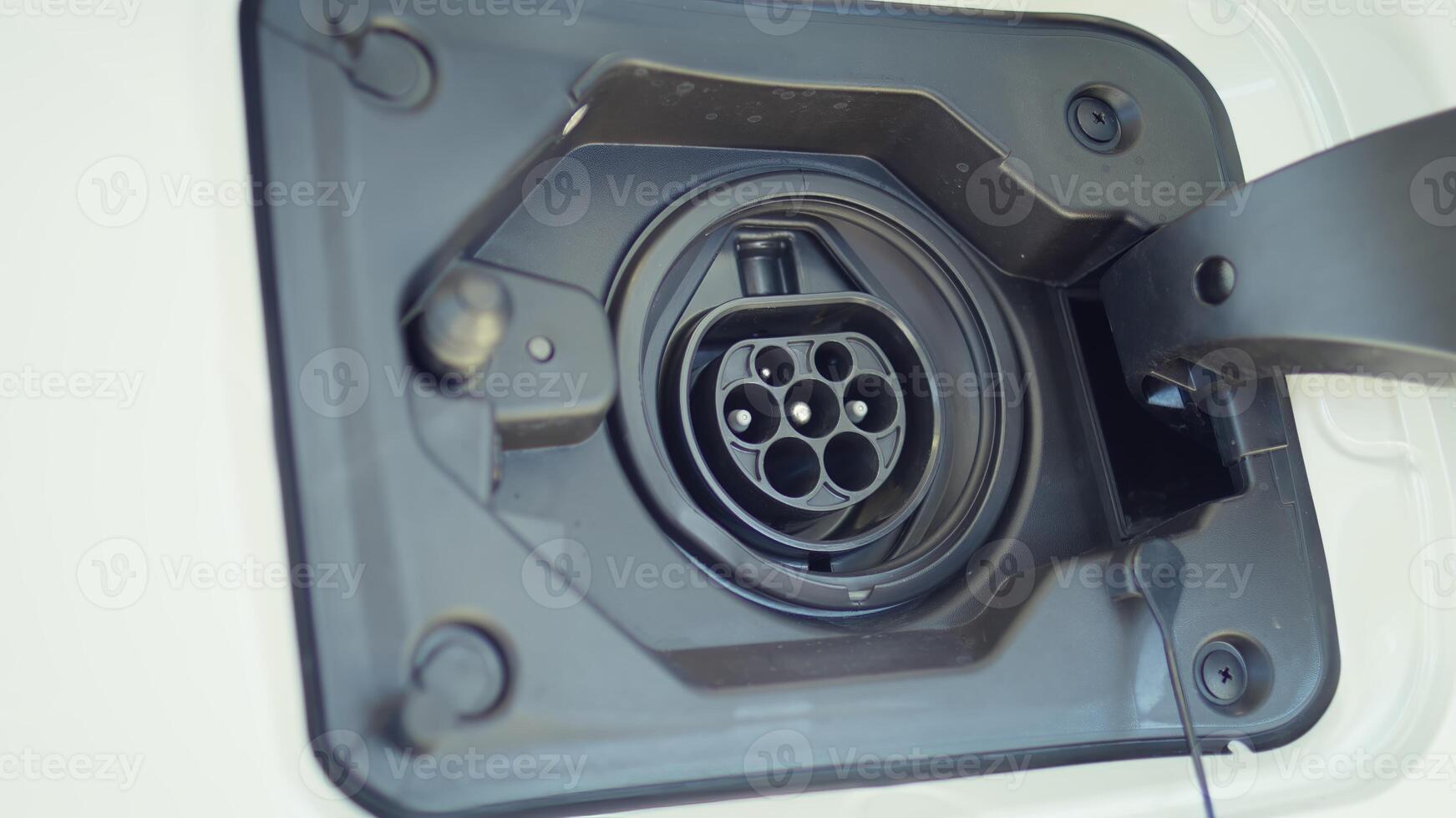 Extreme close up shot of electric car charging port cover opened to recharge depleted battery. Focus on driver unlocking charging port door cap, preparing to supply EV automobile photo