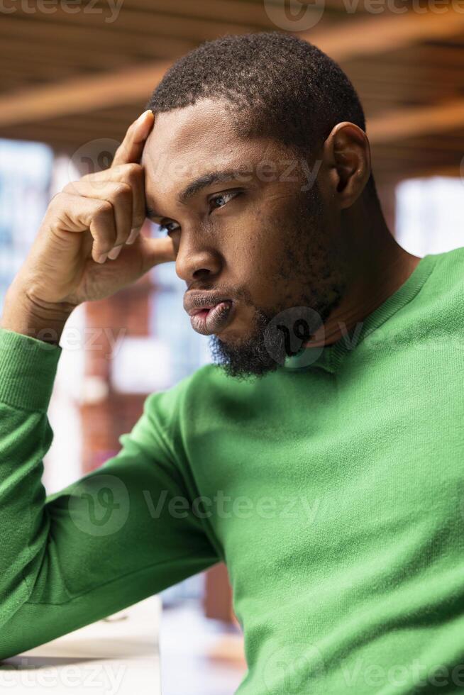 Irked man in apartment office sighing, upset after having to answer too many emails on laptop. Annoyed freelancer feeling overworked while typing on device keyboard, feeling frustration photo