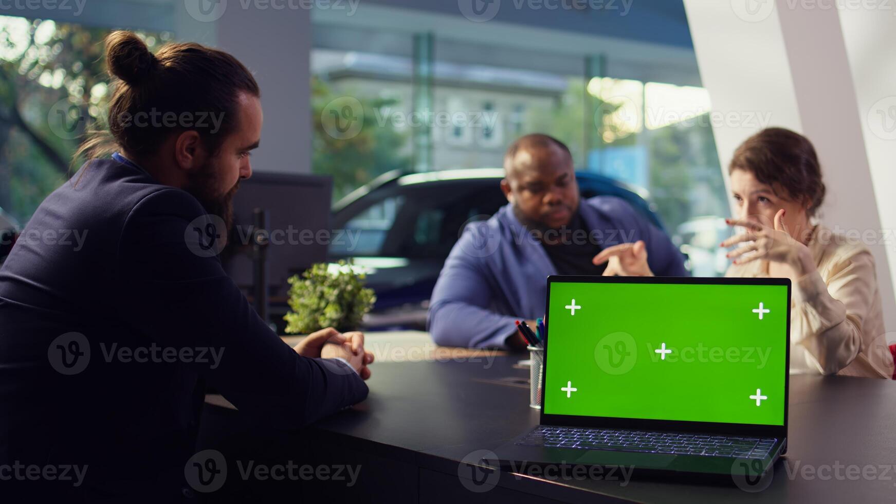 Dealership salesperson looking over appointment list on green screen laptop spreadsheet to schedule car test drive for customers. Showroom agent organizing test drive using mockup notebook, camera B photo
