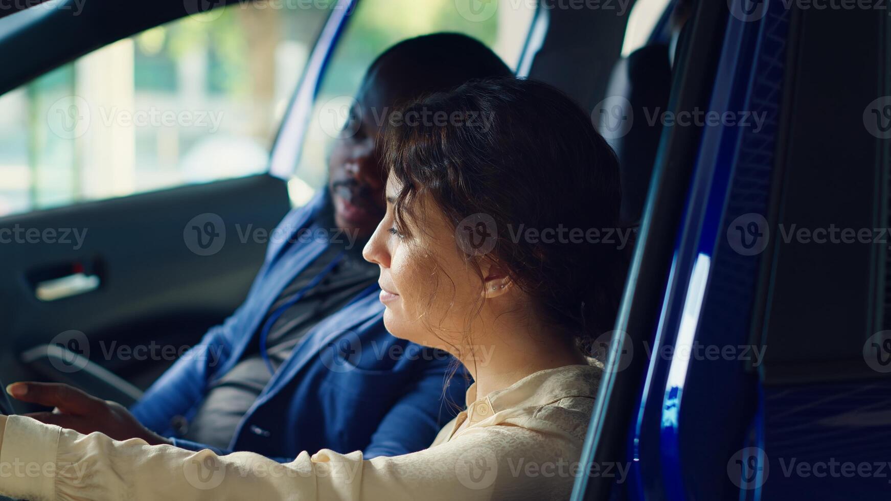 Man arguing with showroom salesperson after observing issues in vehicle during test drive. Upset woman at steering wheel next to husband telling agent concerns noticed after driving car, camera A photo