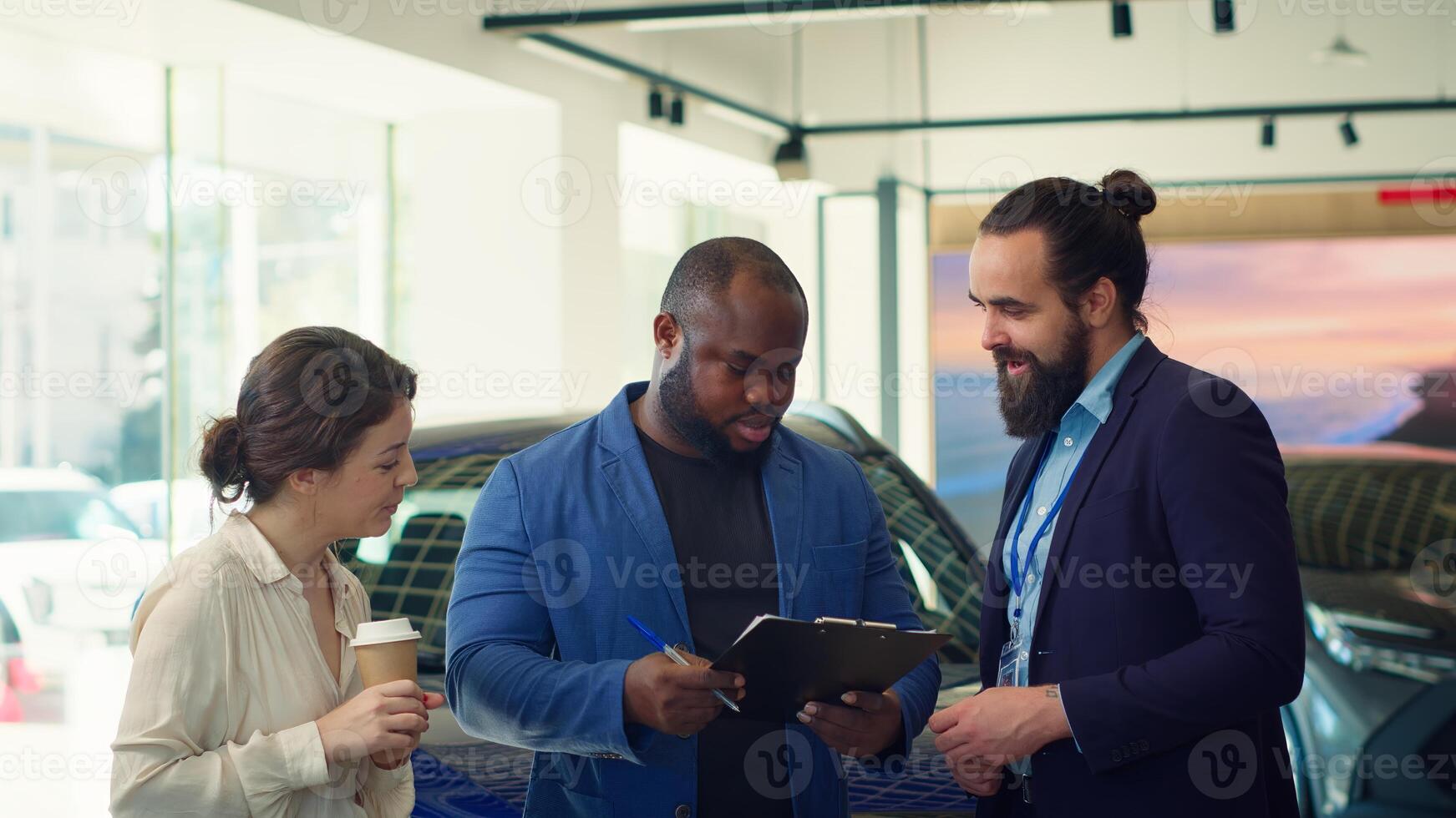 Car dealership salesman giving sale contract for satisfied clients to sign after conducting test drive. Showroom agent suggesting clients extra features to buy, asking for signature, camera A photo