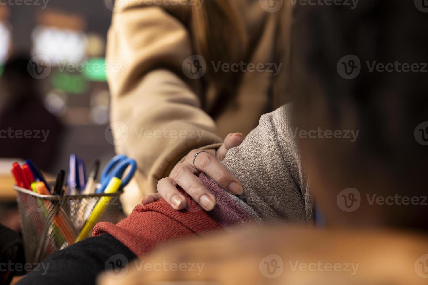 Young girl wakes up her colleague in the campus library after falling asleep on her books and study materials, sleep deprived student. Pupil feeling tired with burnout, studying all night. Close up. photo