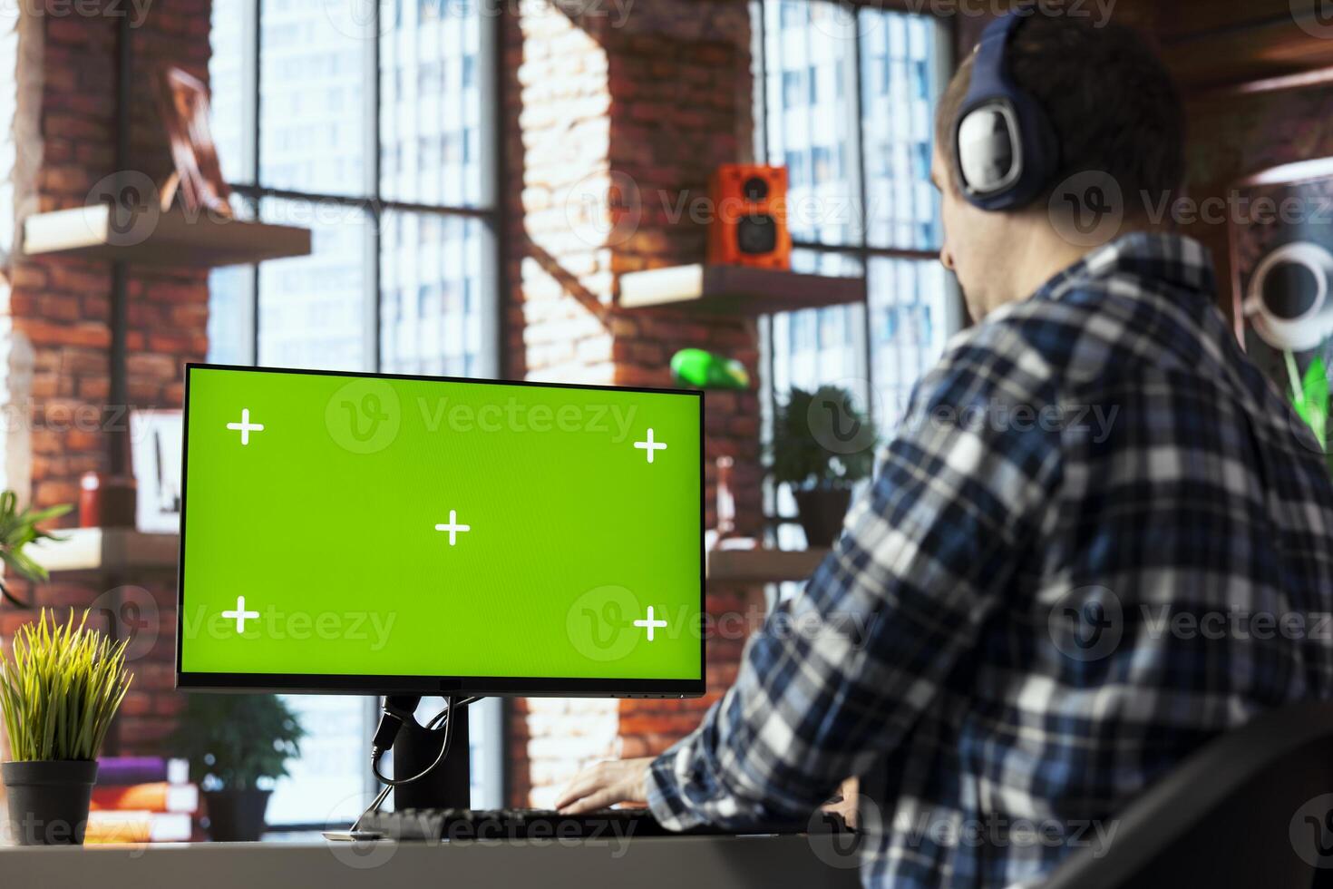 Freelancer listening music, analyzing data on isolated screen PC monitor at desk, compiling analytical reports. Employee wearing headphones using chroma key computer display, finishing project photo