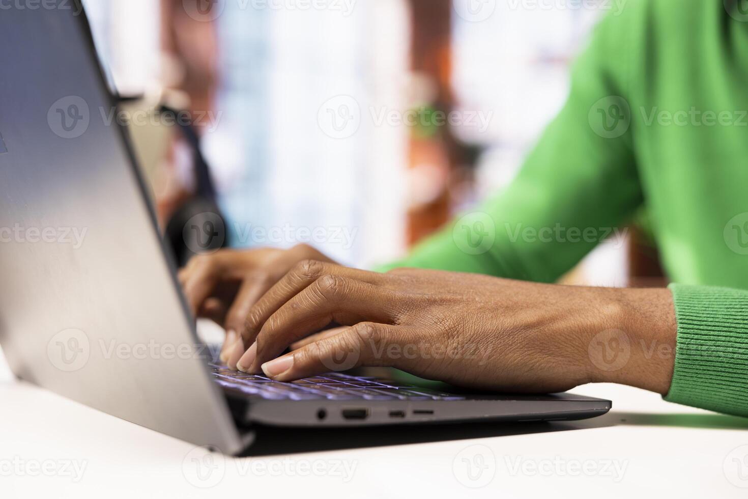 Remote employee seated at home office desk using notebook, checking emails displayed on screen, reading messages in inbox. Close up of teleworker managing electronic correspondence, typing on keyboard photo