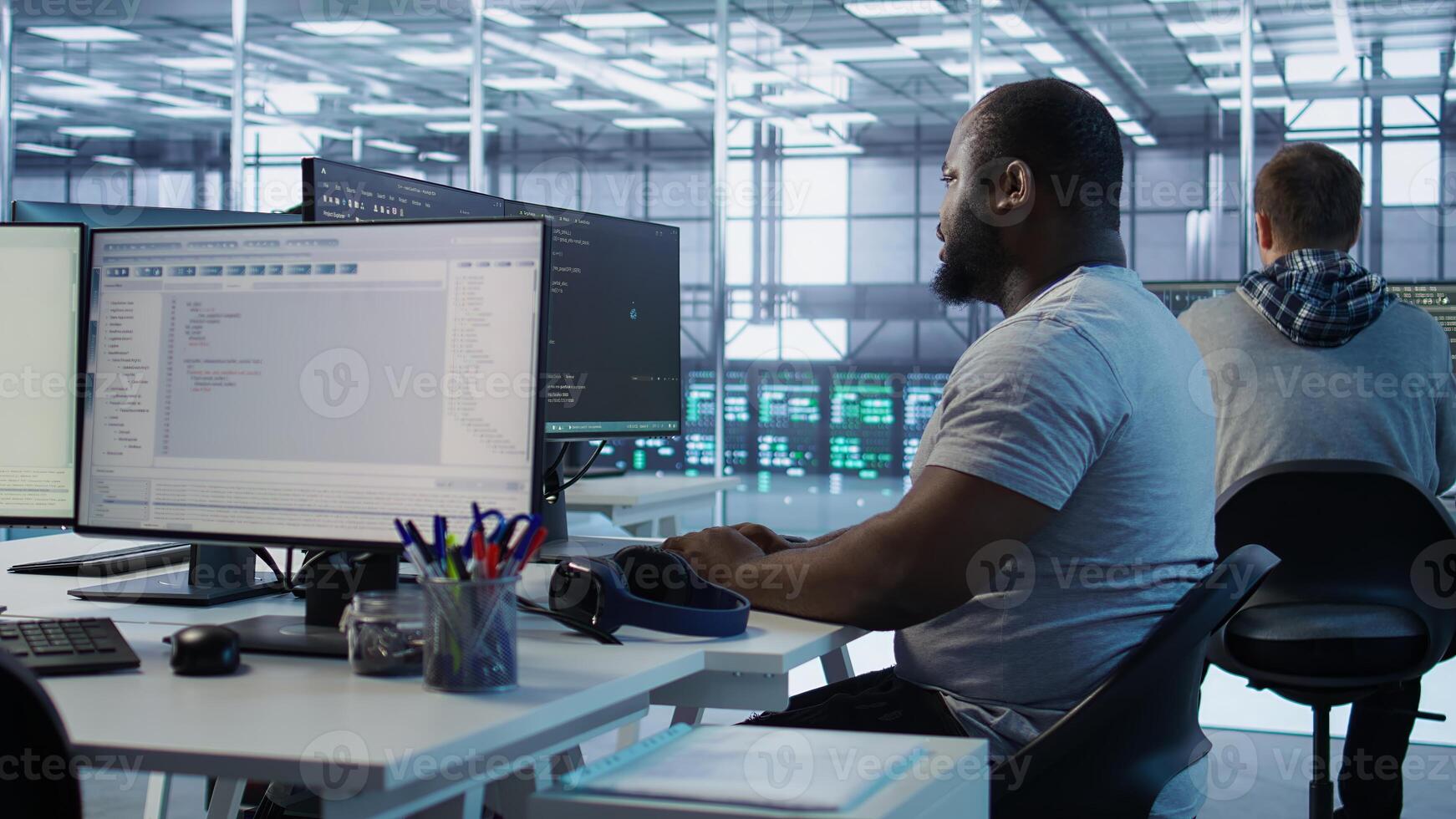 Engineer writing code and doing checkup on server room providing computing resources for different workloads. Man investigating data center mainframes using computer, camera B photo