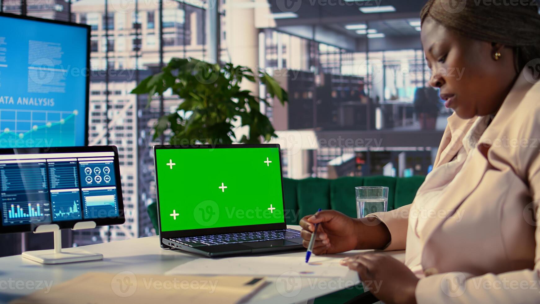 Black entrepreneur looking at isolated mockup screen in high end office space, ambitious director with executive power. Female director showcases strategic thinking within the enterprise. Camera B. photo