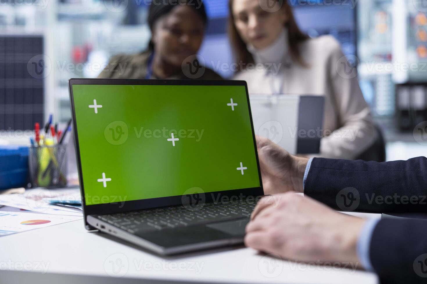 Factory employee works on green screen laptop next to executives discussing solar panel automation strategies. Worker typing on mockup notebook next to team enhancing manufacturing processes, Close up photo