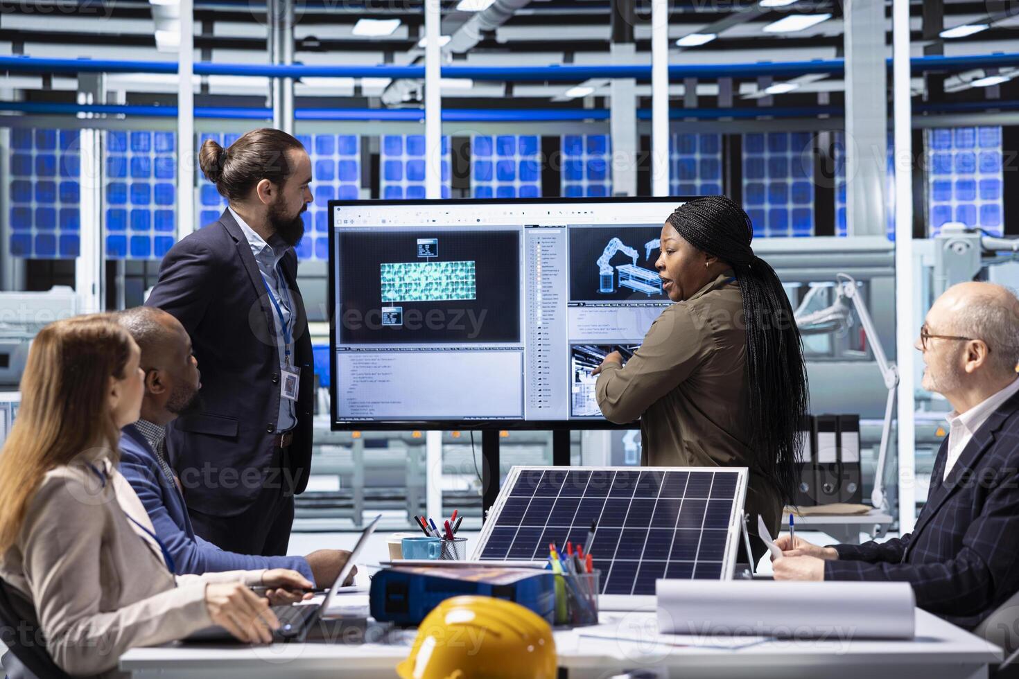 Factory management executives discuss solar panel technology and automation strategies, analyzing data to enhance sustainable manufacturing processes in advanced industrial facility photo