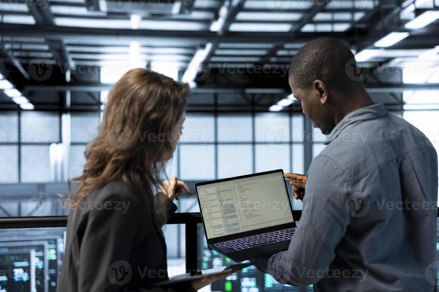 Programmers using laptop in data center, managing server virtualization, running scripts. IT experts using programming language on notebook in server hub, finetuning network protocols photo