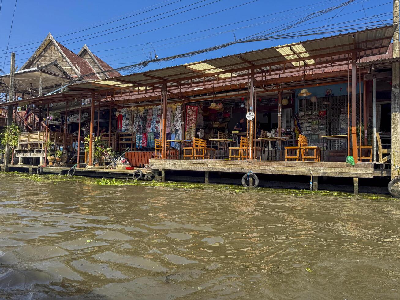 Bangkok, Thailand - November 12, 2024. Tourists exploring a floating market in Bangkok, floating bazaar with boats with Thai cuisine. Local produce on the canal offer unique experience. photo