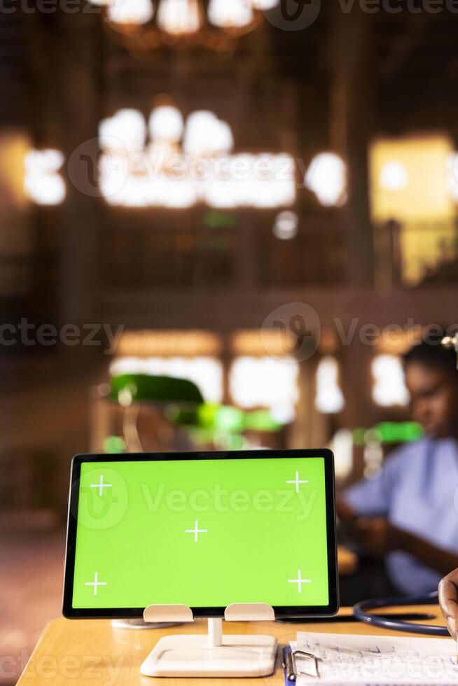 Black medical scholar reviewing case files in the library next to chroma key screen, preparing for a lecture or study session on medical practices. Med school pupil learns for a career. Close up. photo