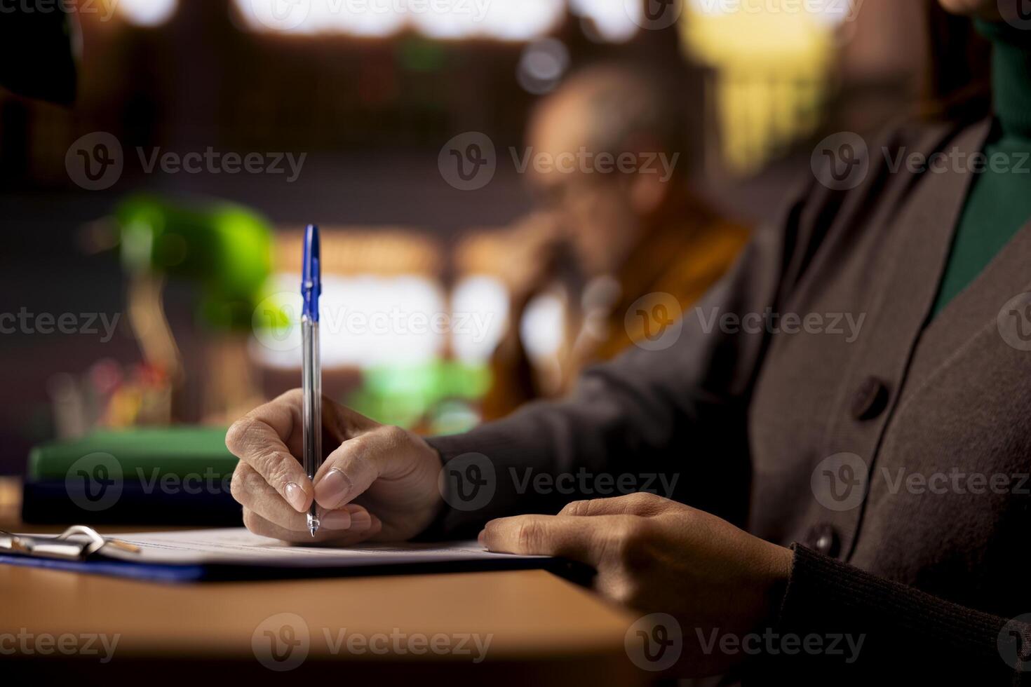 Mature person at a college campus study area writing notes and ideas, focused on her academic graduation preparation at the library. Female student learning for personal goals. Close up. photo