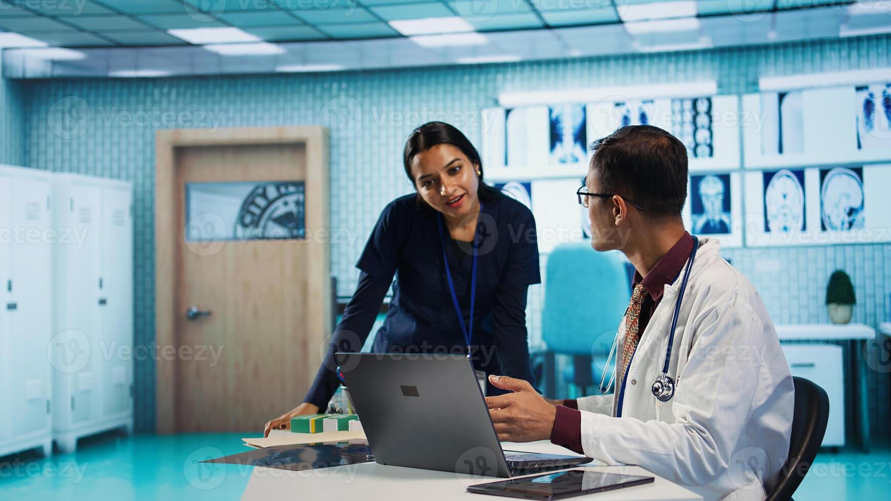 Indian professional medic sharing a high five with his nurse, medical expertise at a facility. Hospital staff reviewing x ray and MRI scan results and focusing on diagnostics report. Camera B. photo