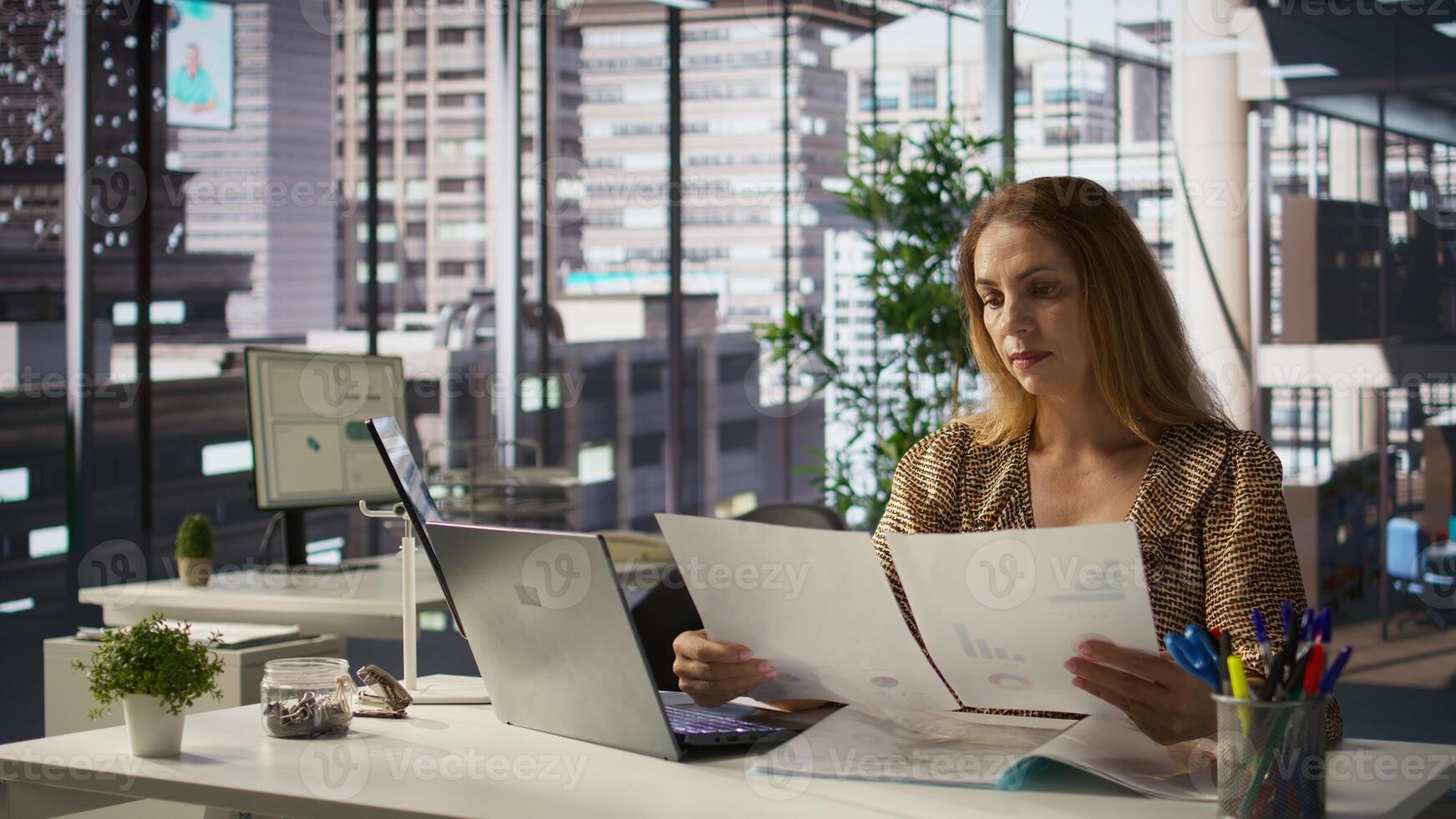Business sales manager at work finalizes strategy planning in her office, doing report writing and answering emails. Worker collaborates on project management, uses data to drive decisions. Camera B. photo