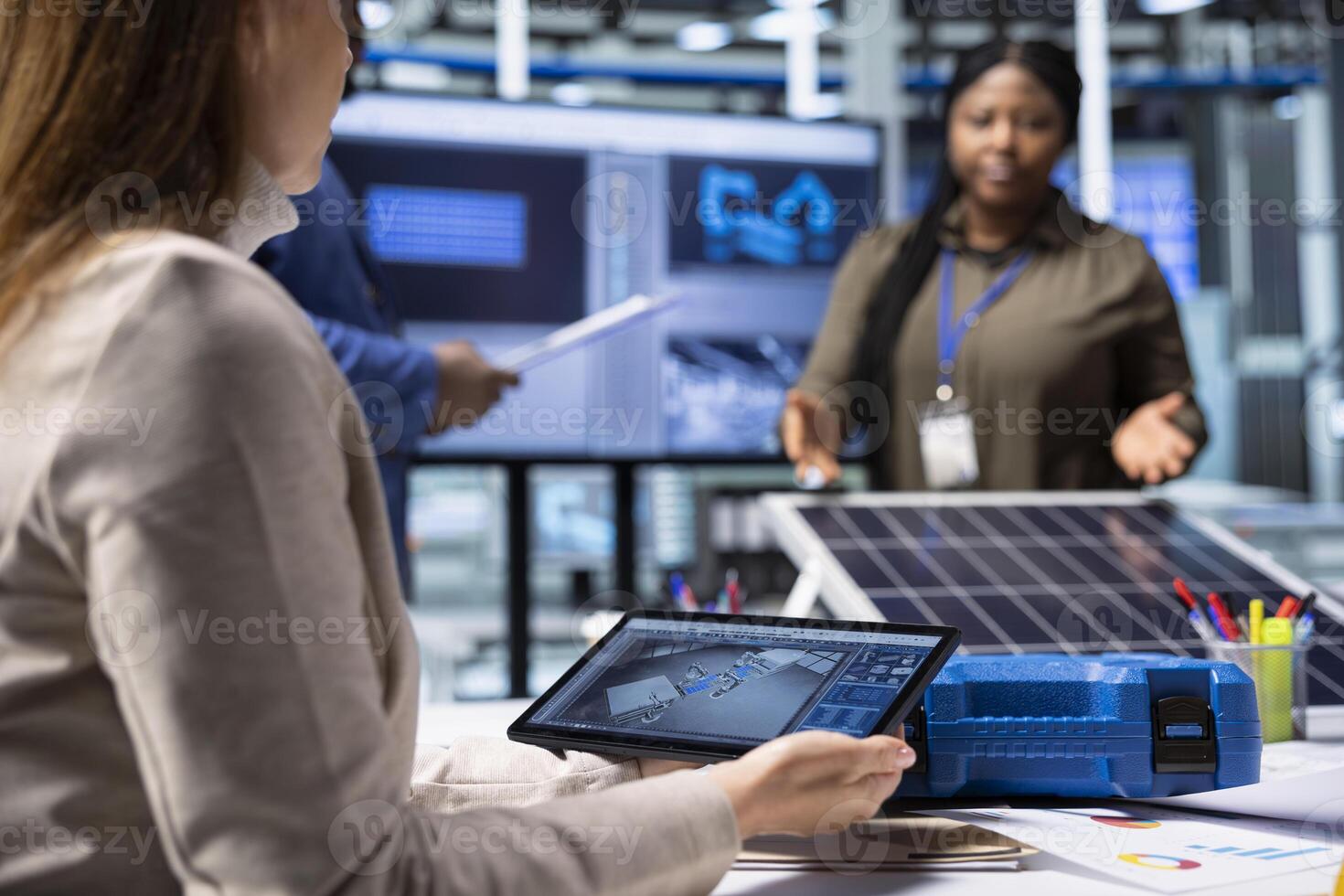 Photovoltaics factory researching team monitoring system performance using tablet. Solar panels plant management executives tracking energy production using device software photo