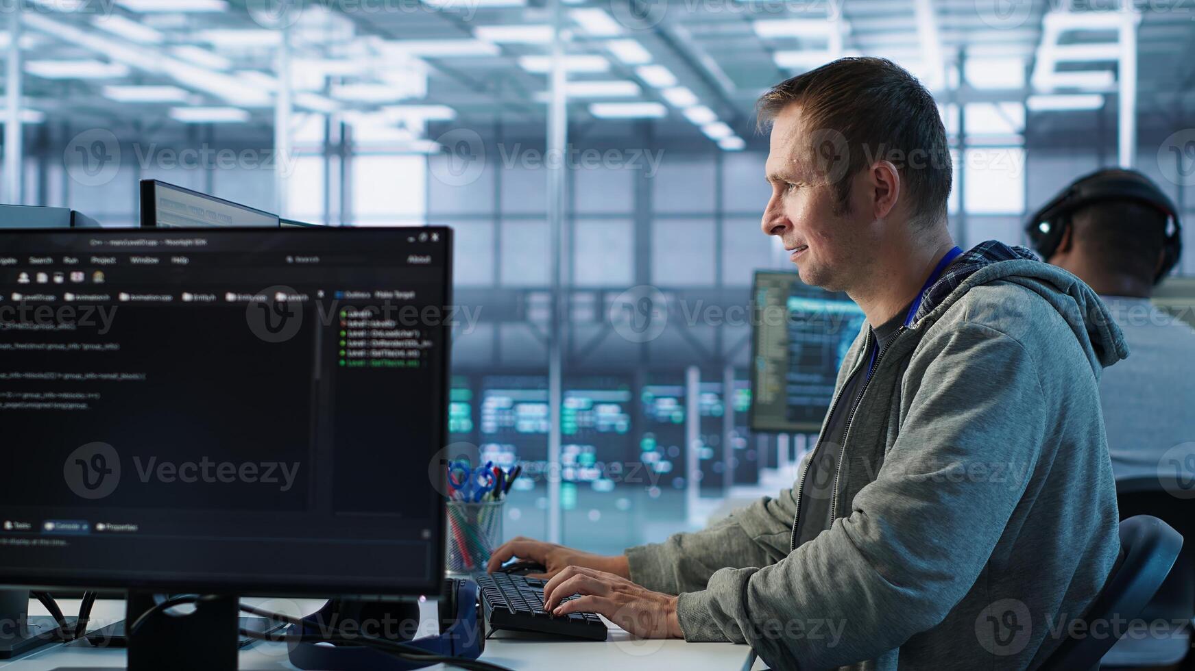 Man working in server hub capable of processing vast amounts of data. IT programmer at PC desk typing on keyboard, updating servers controlling network resources, camera A photo