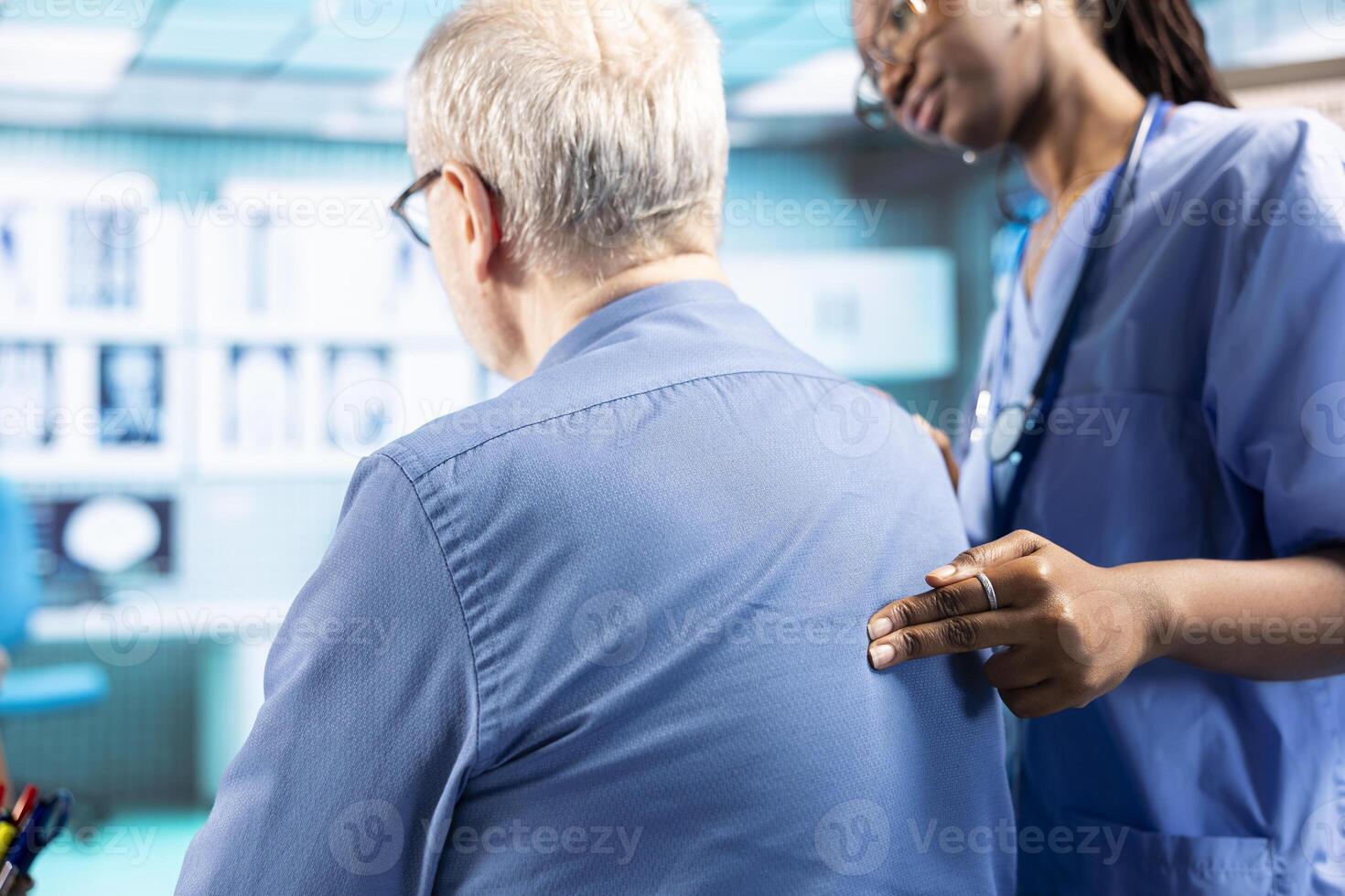 Female medical assistant performs a posture assessment on old man, focusing on spinal alignment and muscle mobilization, promoting wellness and addressing pain management in a clinic. Close up. photo