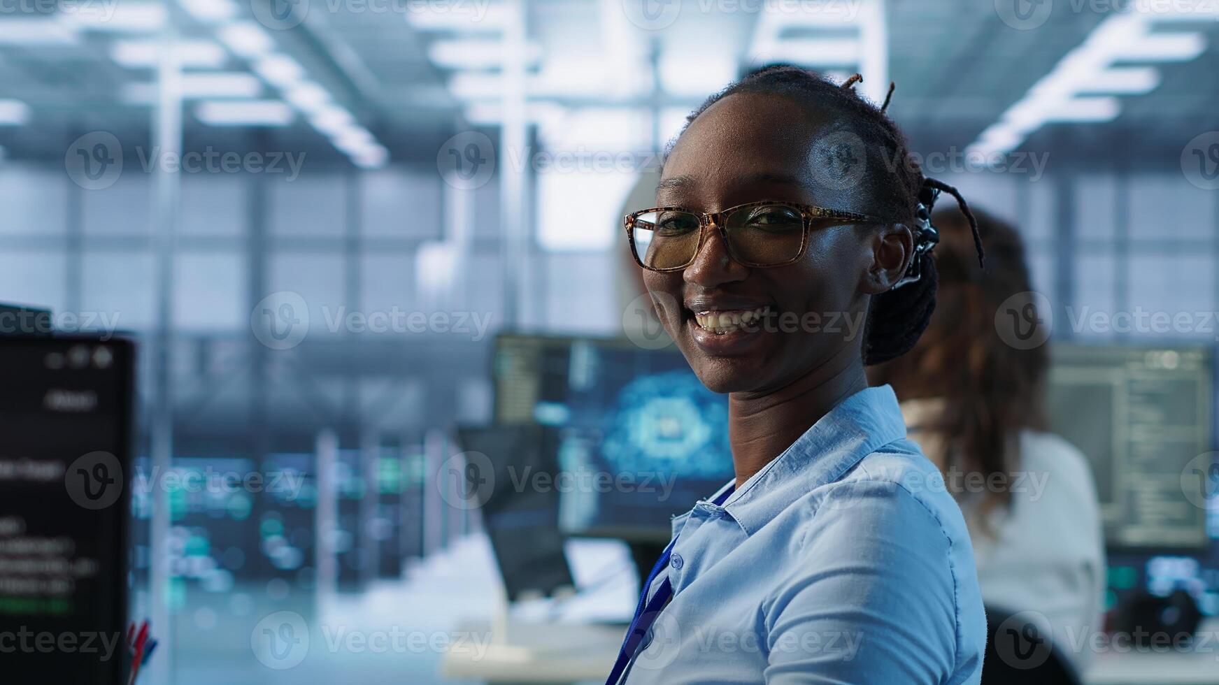Portrait of smiling woman tasked with doing checkup on server room rows providing computing resources for different workloads. Happy admin investigating data center mainframes using PC, camera A photo