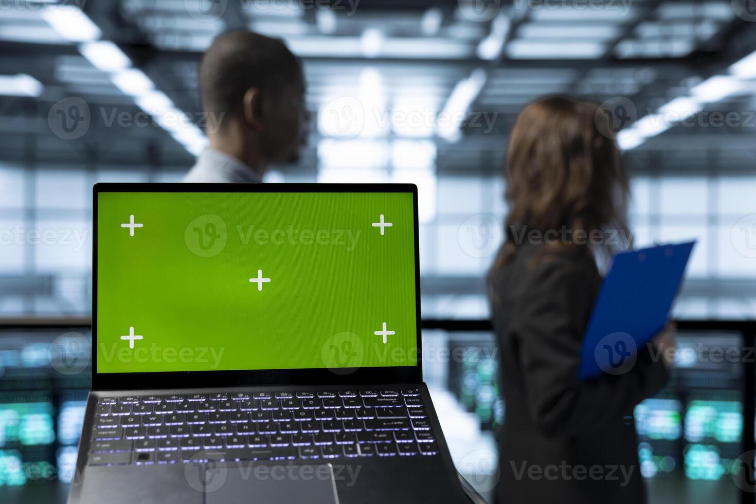 Focus on isolated screen laptop in front of engineers in blurry background doing network virtualization. Close up of mockup chroma key notebook used by admins in server farm verifying settings photo