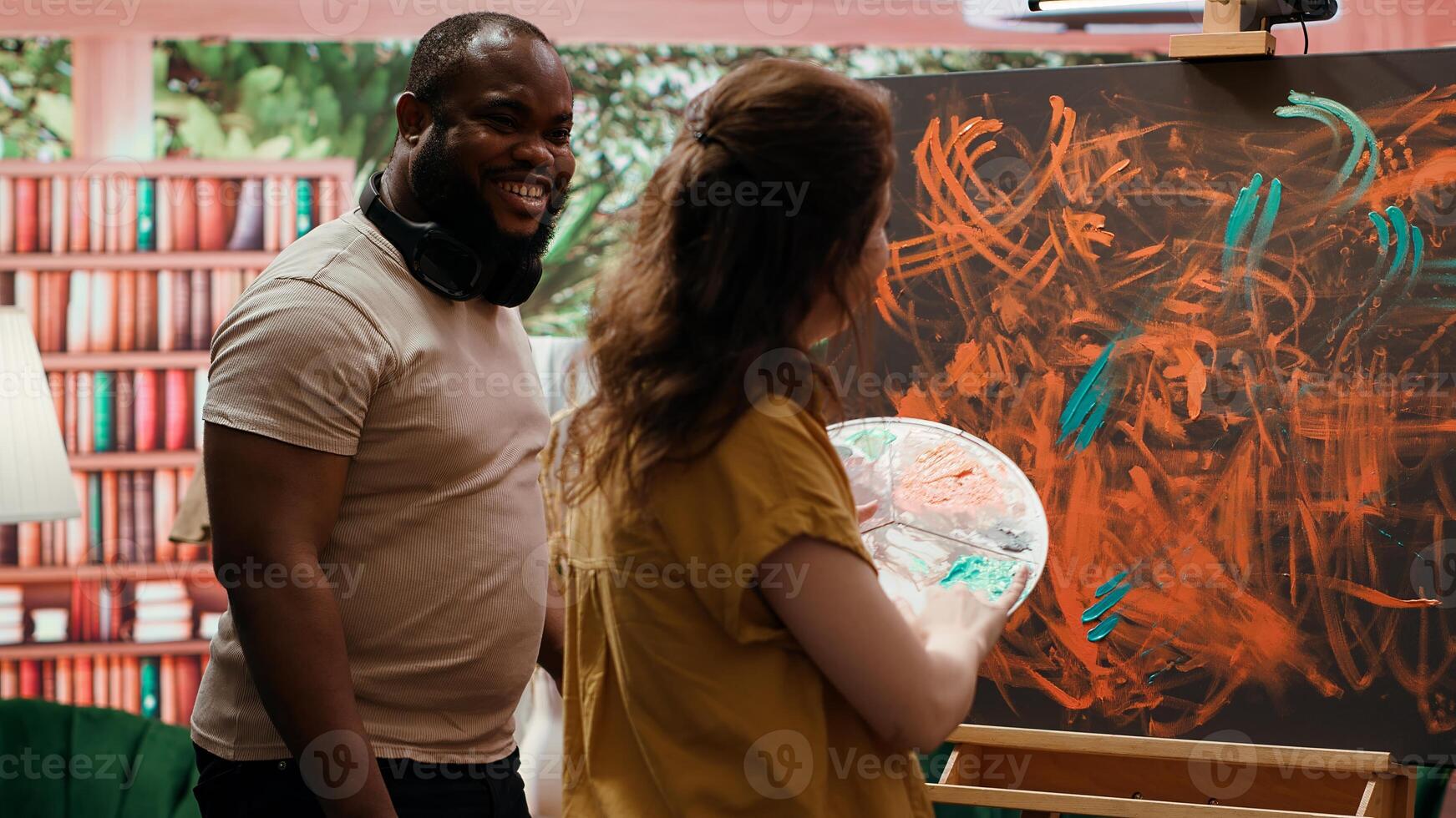 Master painter and apprentice creating a masterpiece with finger paint and handprints, using watercolor paint and mixing in on canvas. Abstract artwork piece for gallery exhibition. Camera A. photo
