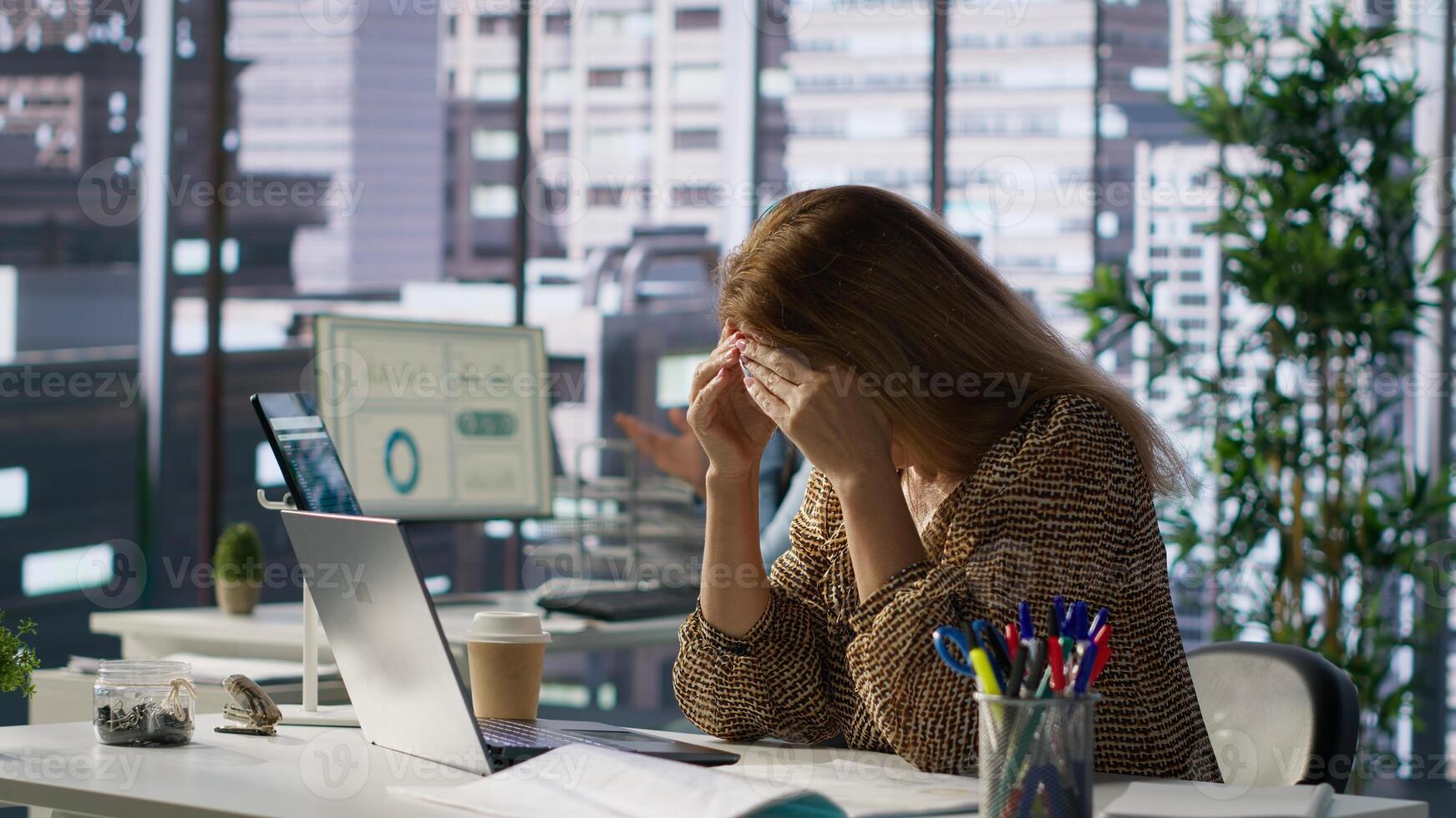 Successful woman battles a headache while managing her financial projects for the enterprise. Employee deals with pressure of meeting objectives, deadlines lead to mental exhaustion. Camera A. photo