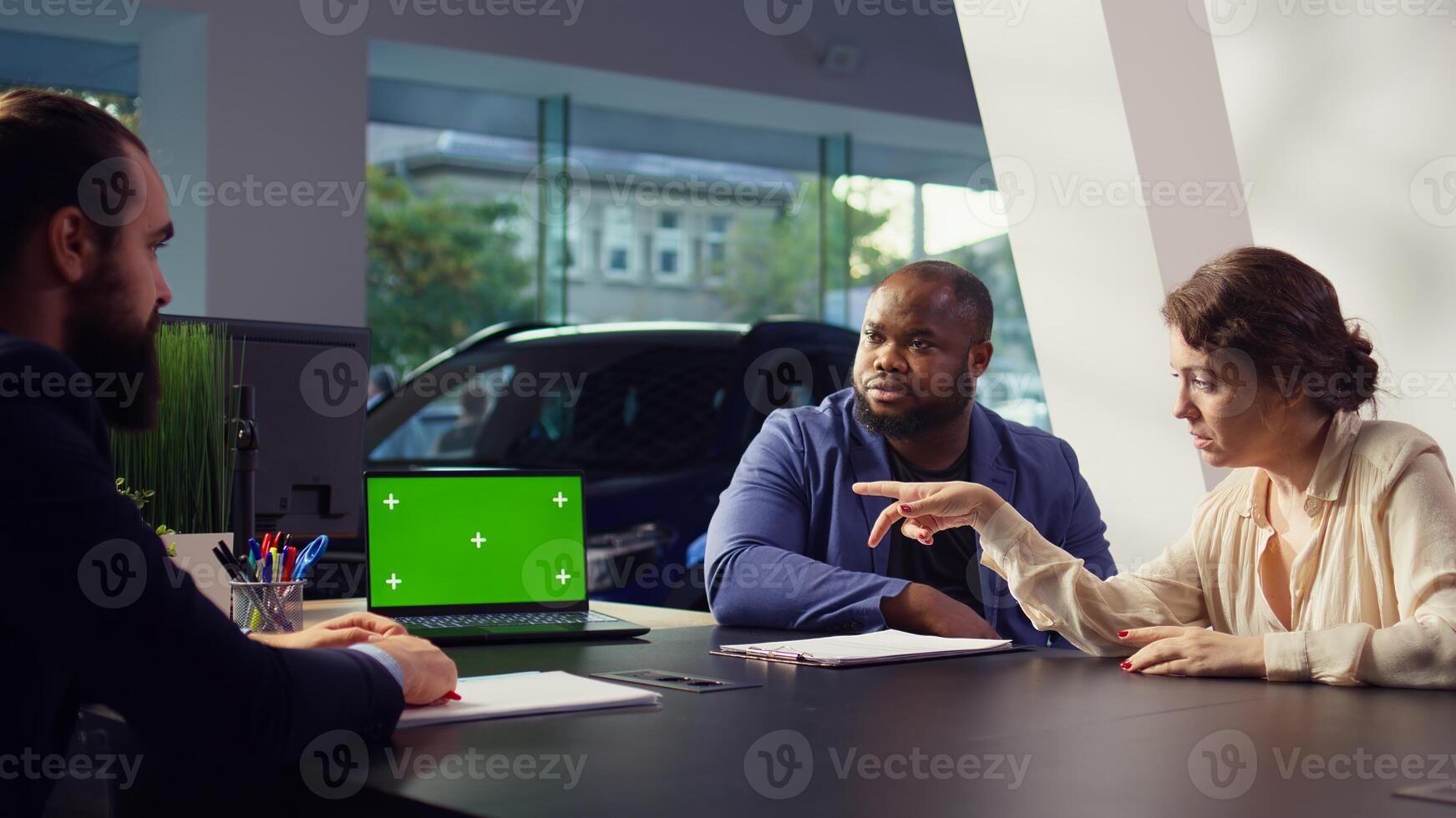 Dealership salesman showing car models on isolated screen laptop to clients, making recommendations. Showroom agent presents financing options to customers on mockup notebook, camera B photo