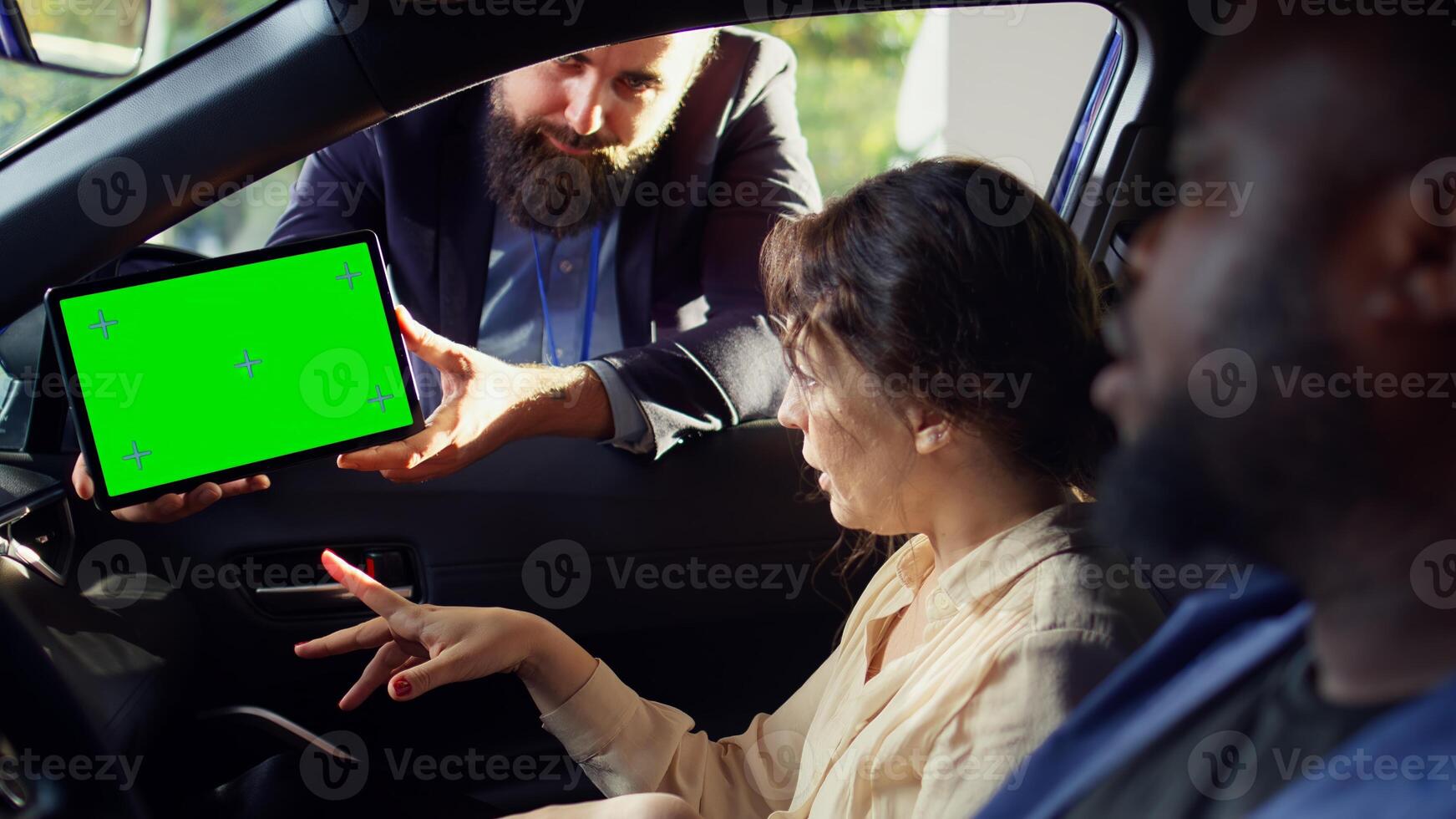 Showroom salesman showing car brochure and price list on green screen tablet to clients after they finished test drive. Dealership agent showing vehicle catalog to customers on mockup device, camera B photo