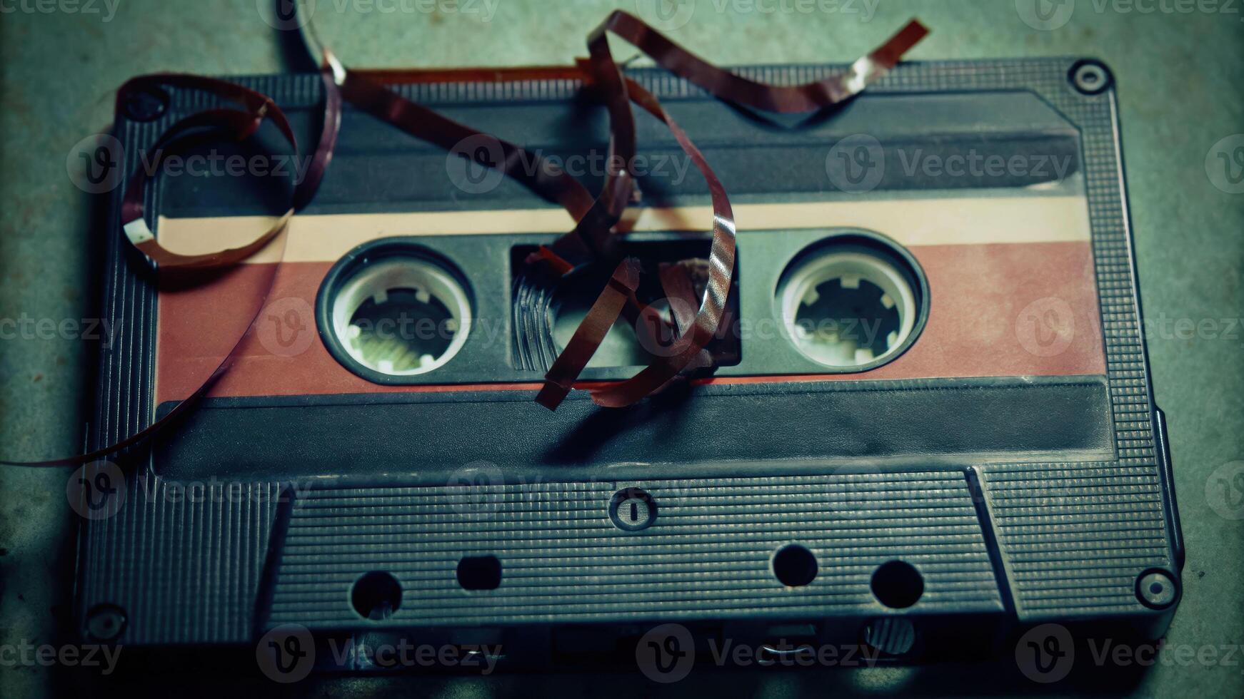 Broken cassette tape exposed on vintage background with magnetic tape and snapped parts nostalgic concept photo