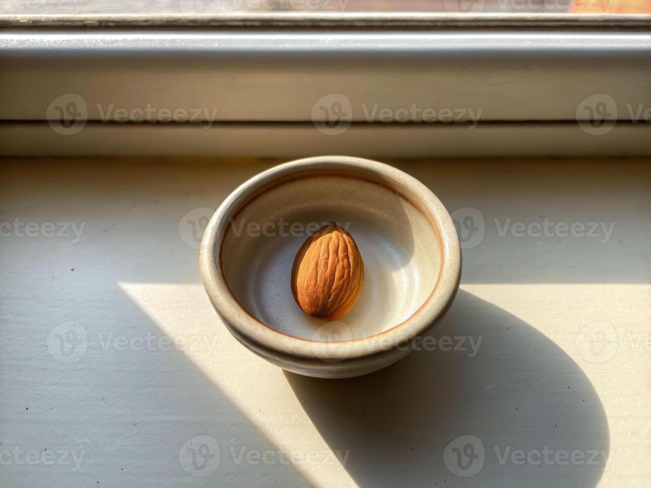 Single almond in tiny ceramic bowl bathed in soft morning light capturing natural serenity photo